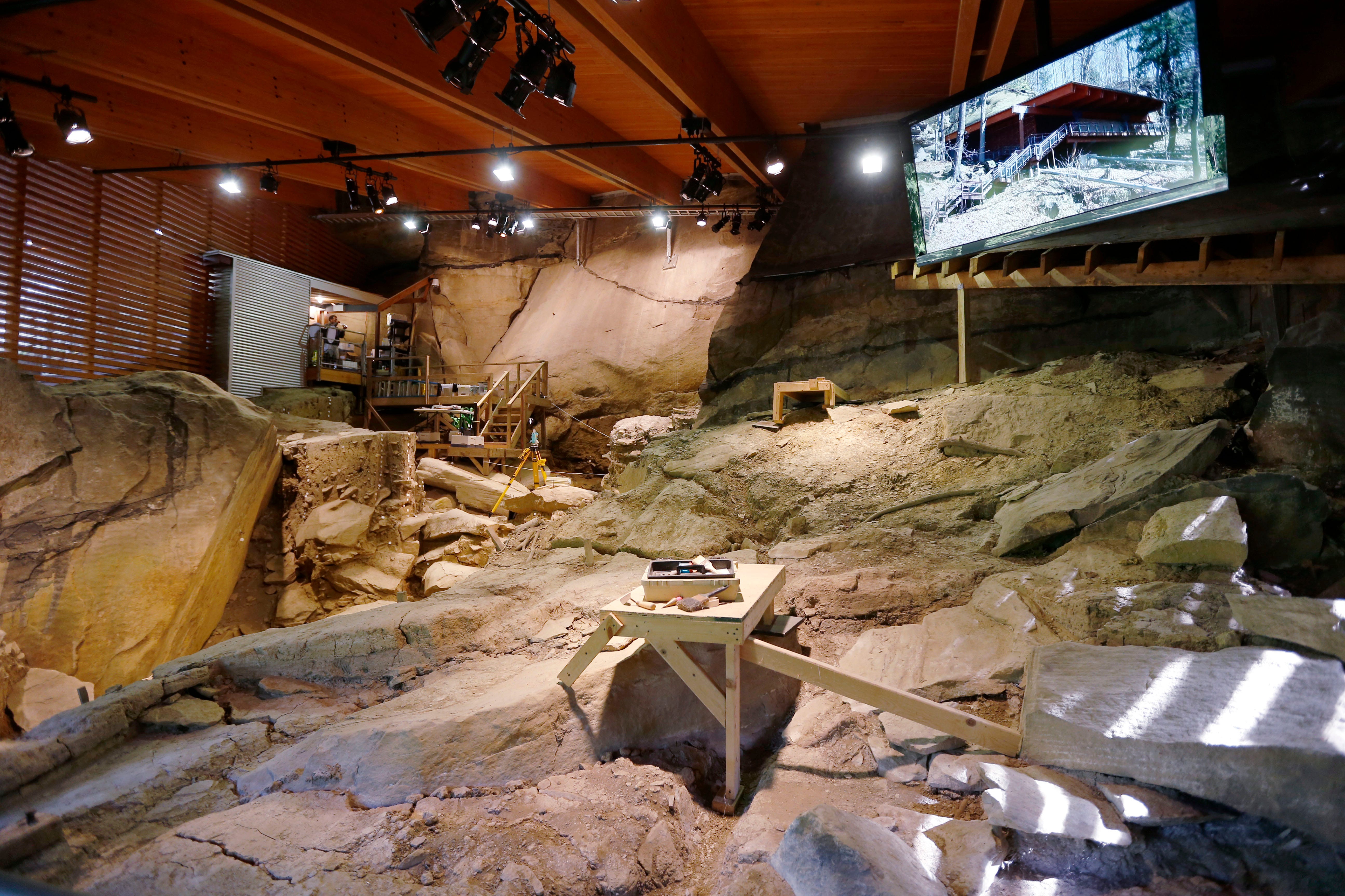 An archaeological site inside a building with a TV monitor hanging over it