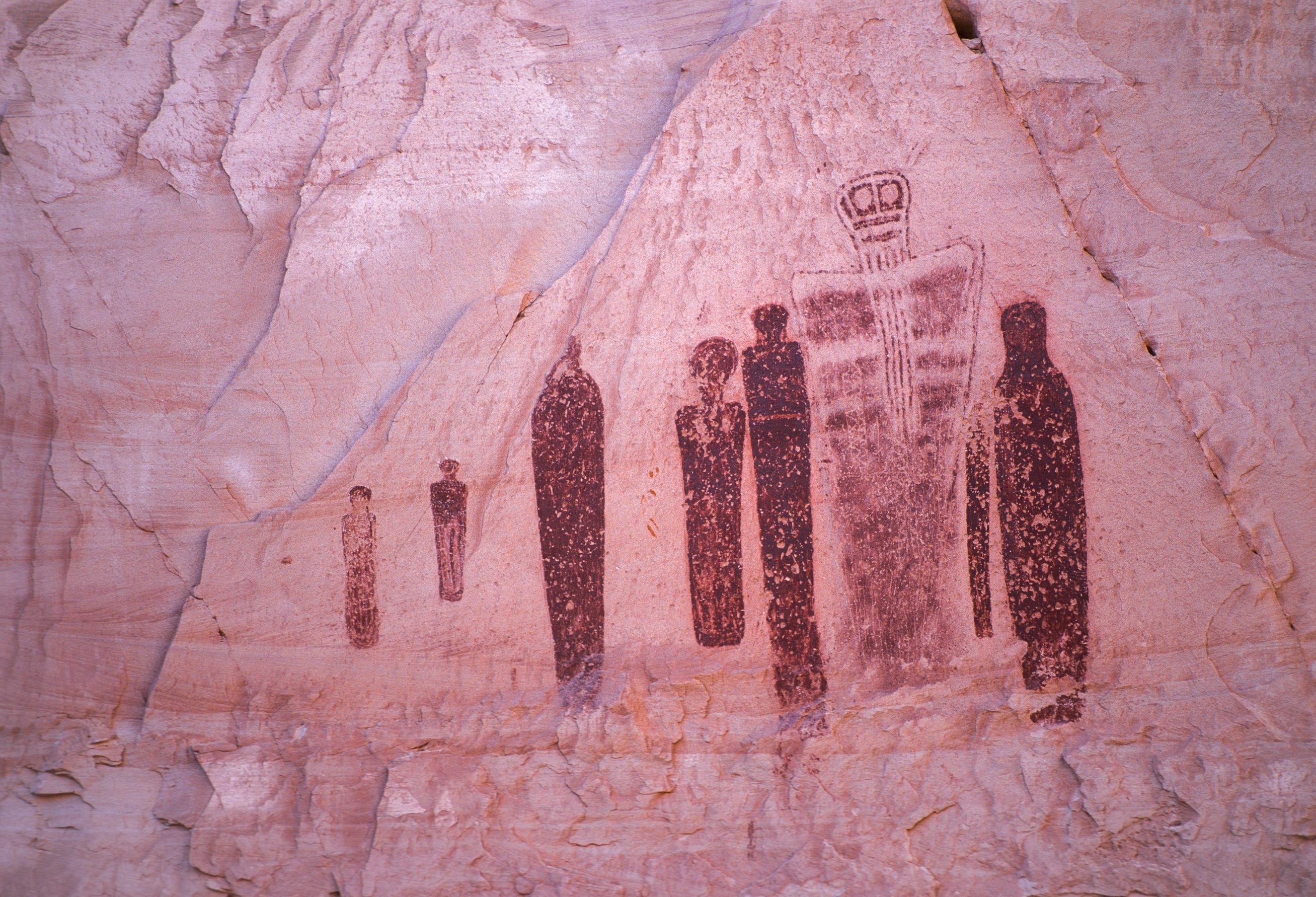 Armless figures depicted on a reddish canyon wall