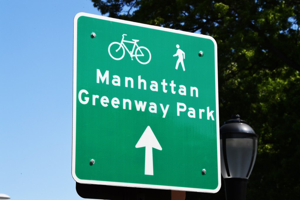 A bicycle and pedestrian sign for Manhattan and Greenway Park.