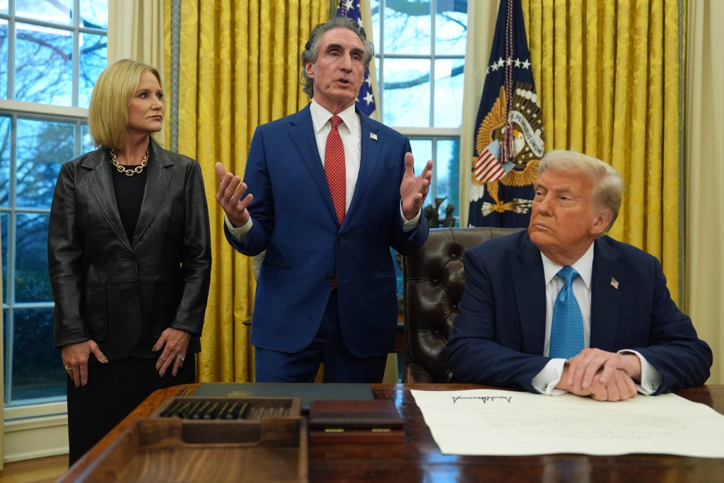 Interior Secretary Doug Burgum speaking in the Oval Office with his wife Kathryn and President Donald Trump listening attentively, taken on January 31, 2025.