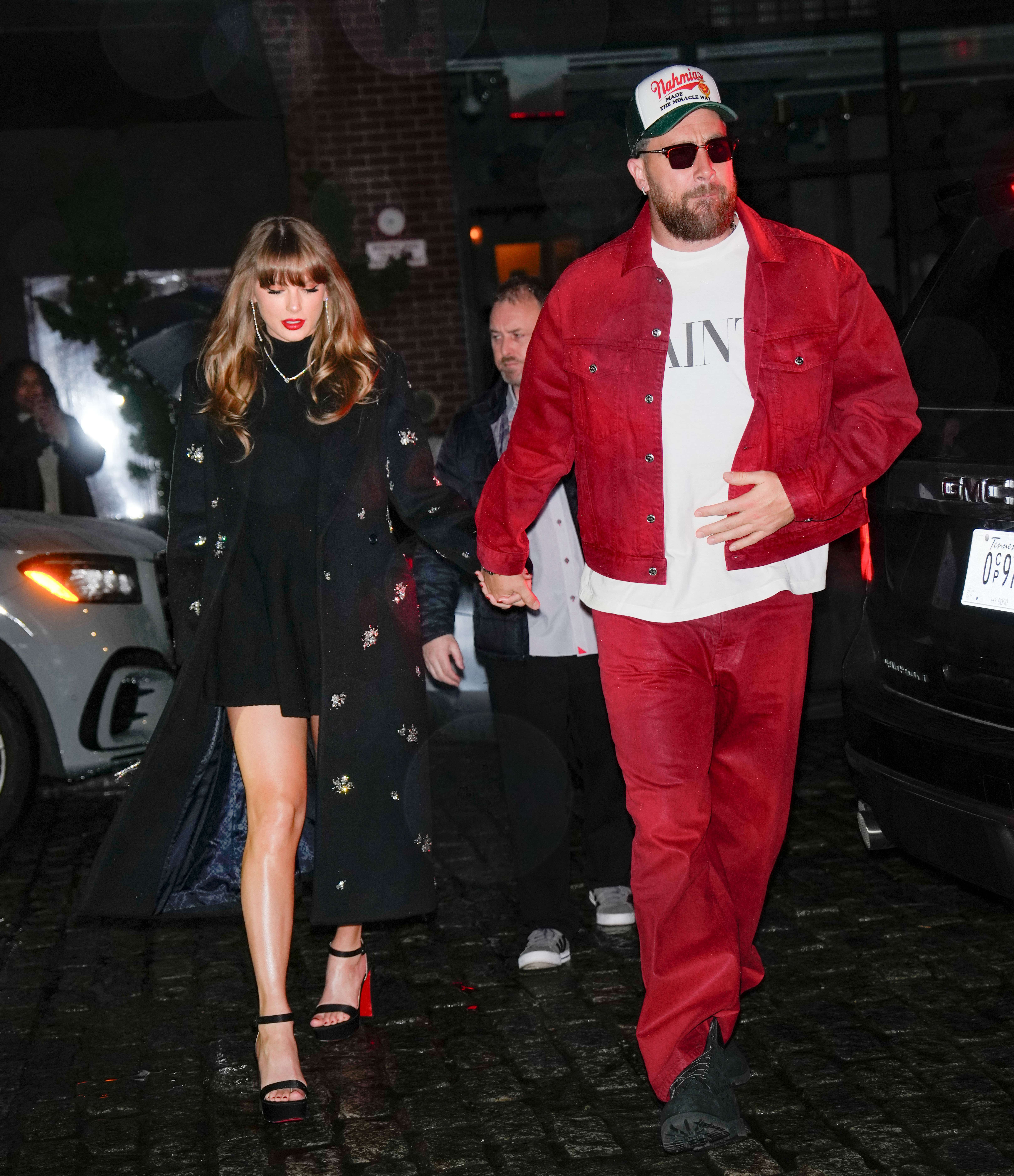 Travis Kelce and Taylor Swift walk at night. 