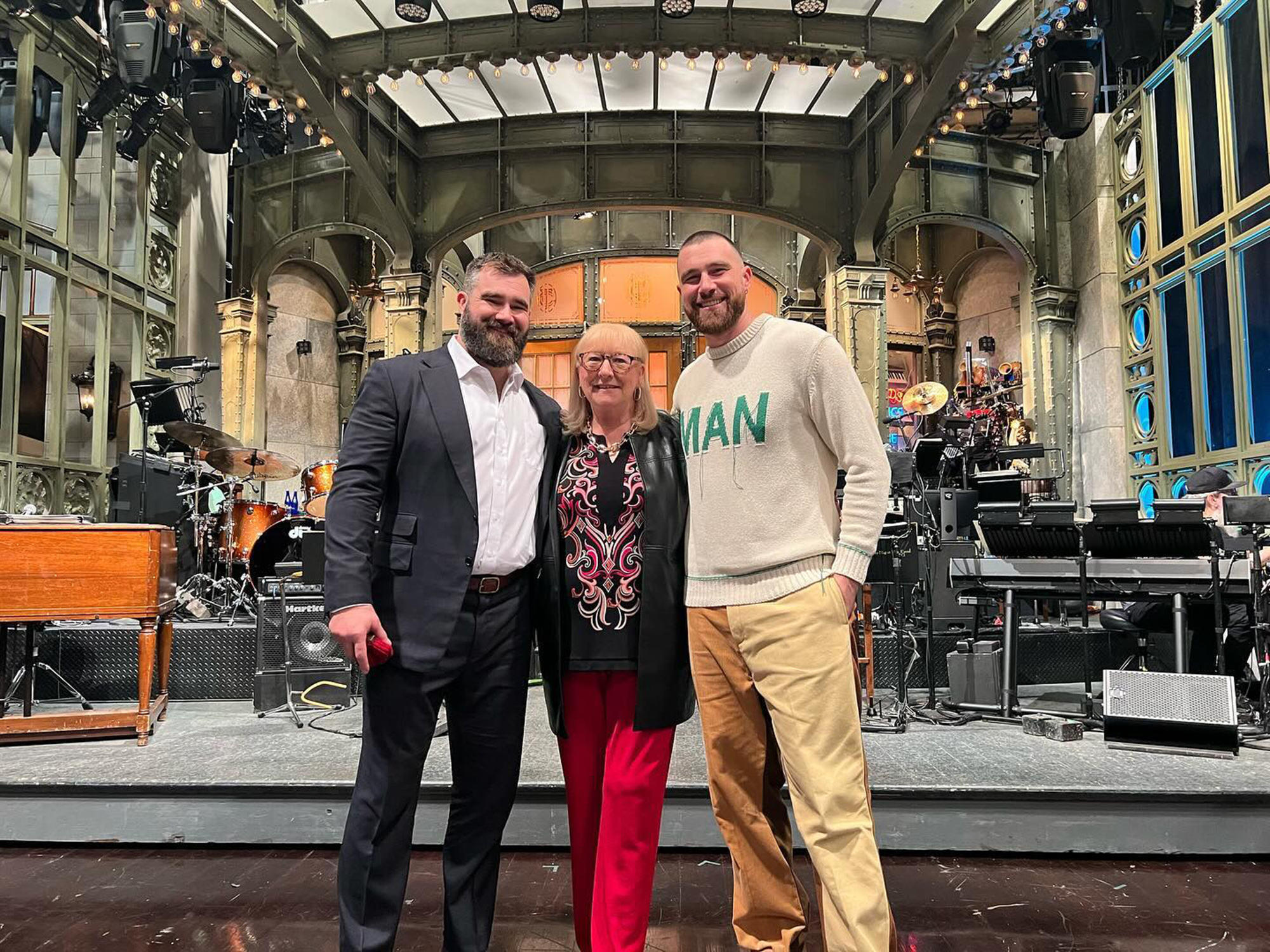 Jason and Travis Kelce pose with Donna Kelce on a stage. 