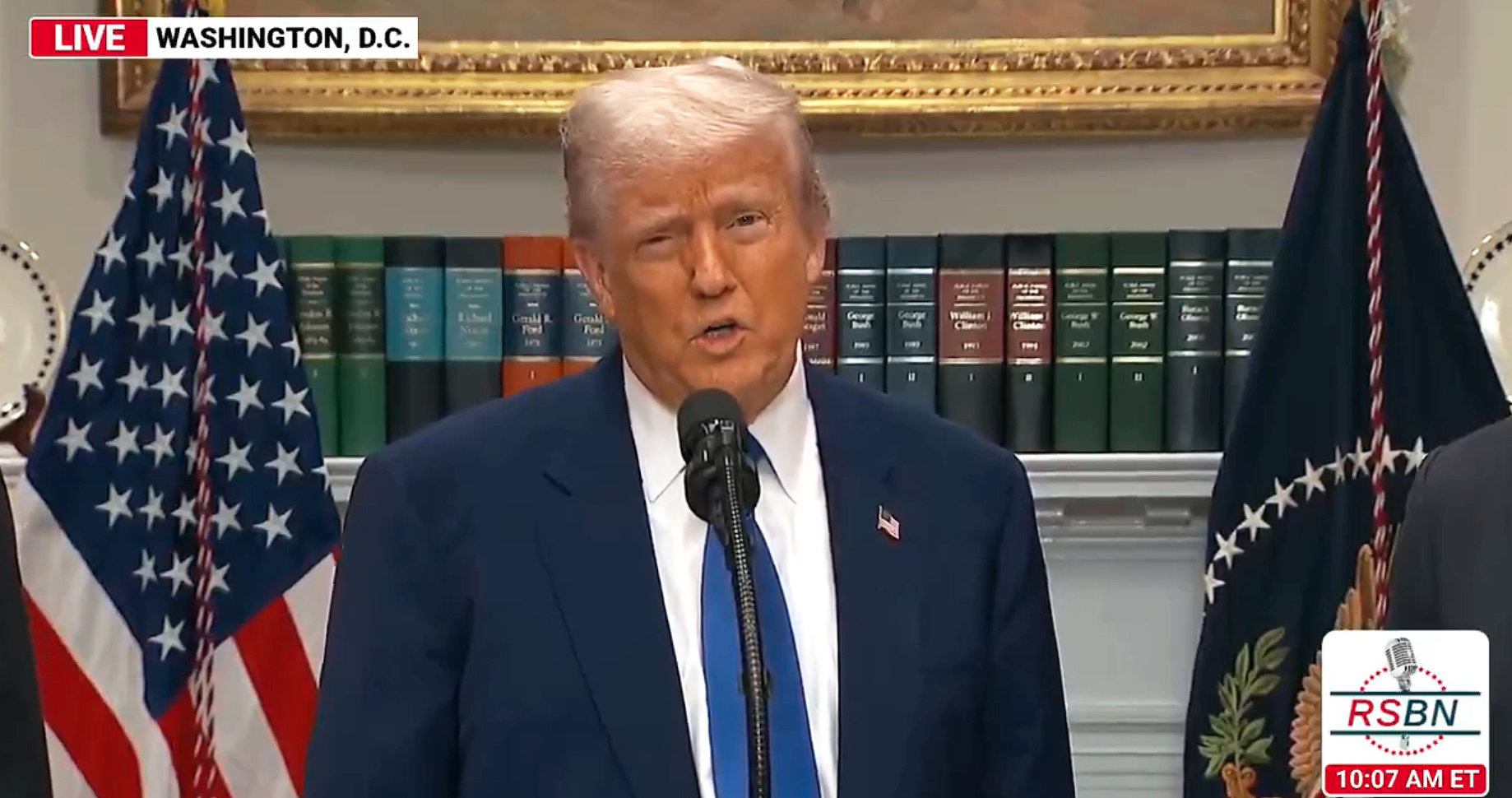 Donald Trump speaks in front of a row of books. 