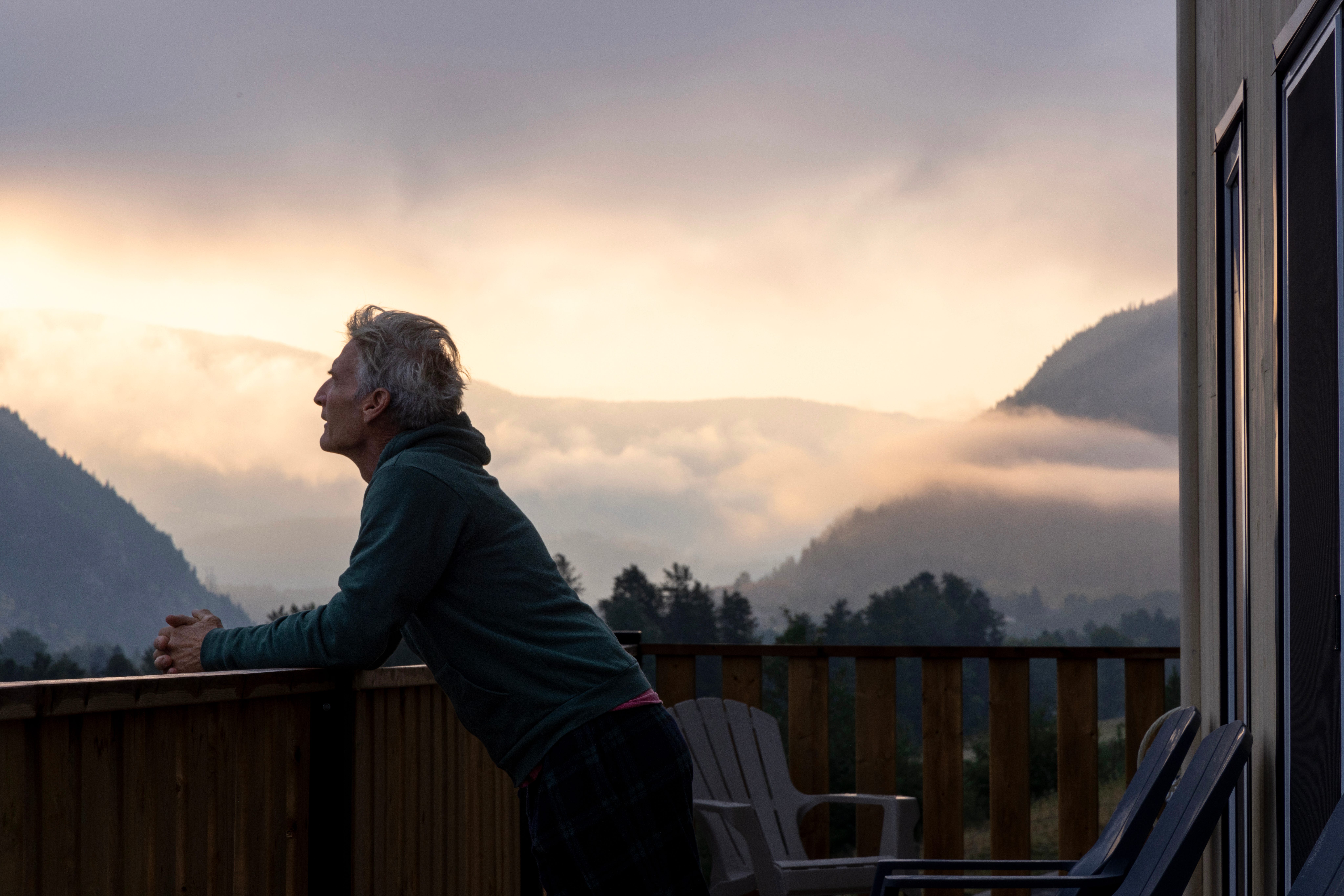 Old man looking at mountains over a balcony