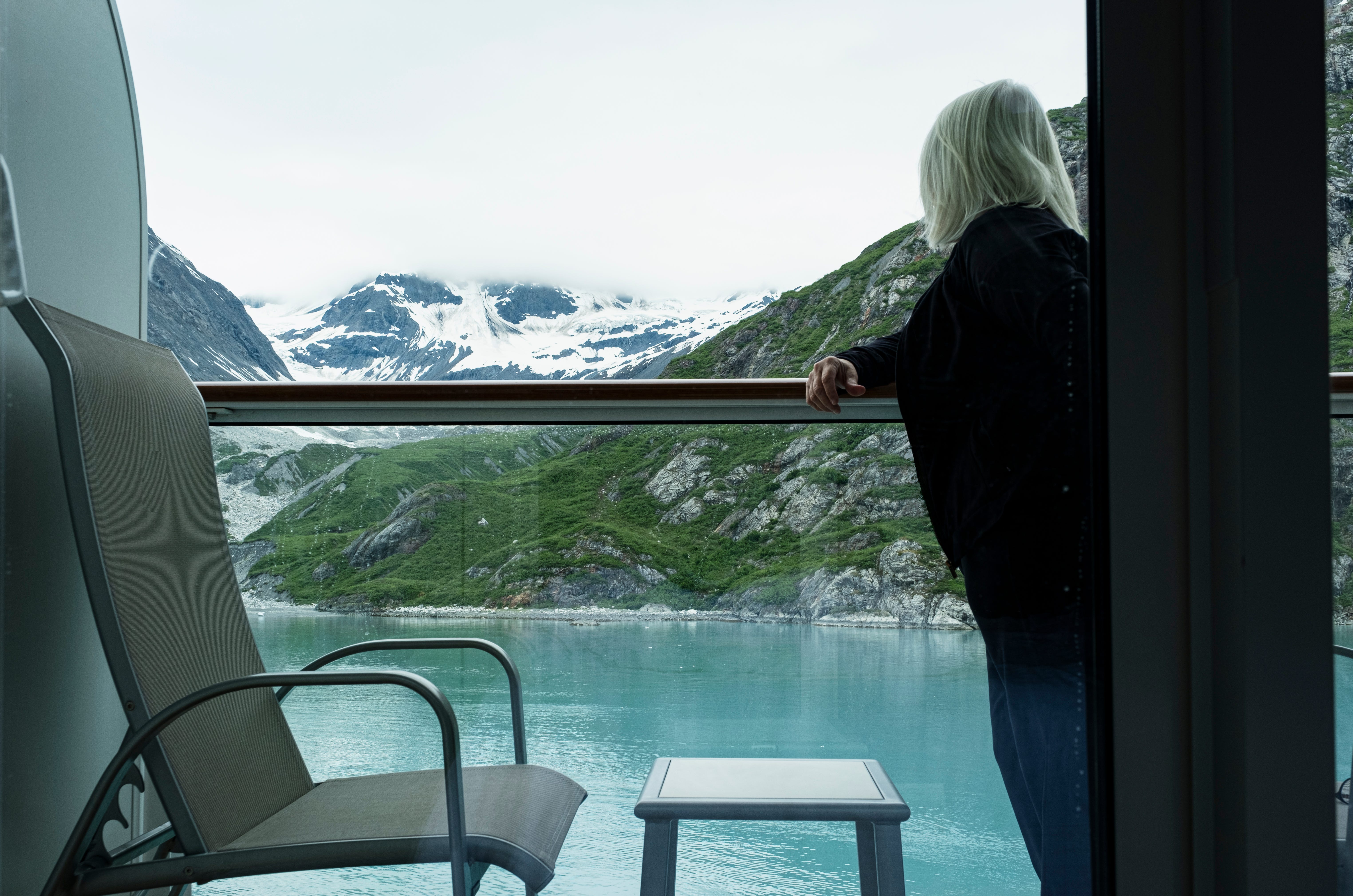 A woman on her balcony on a cruise ship taking in the view of Glacier Bay National Park.