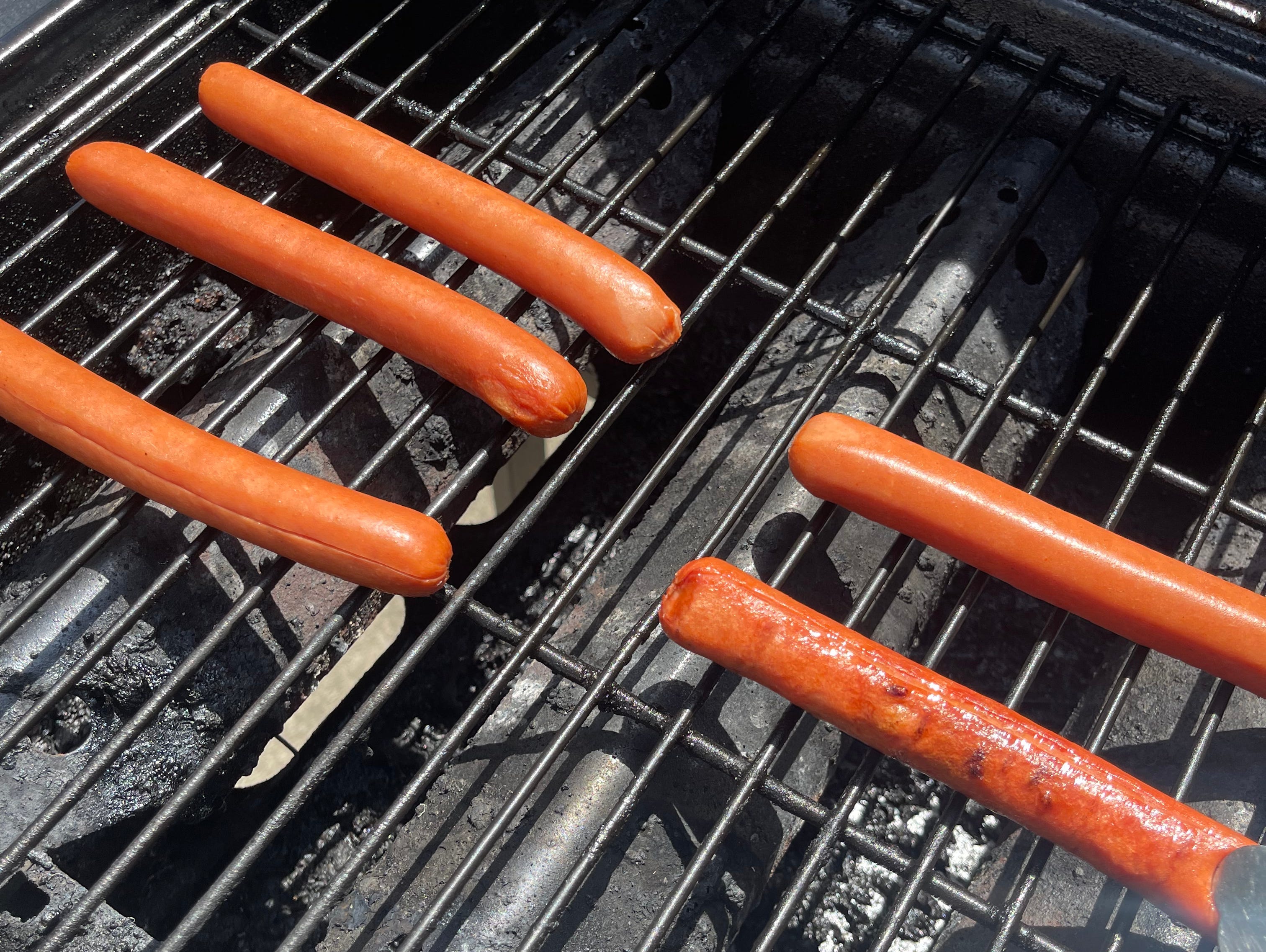 hot dogs grilling on an open grill