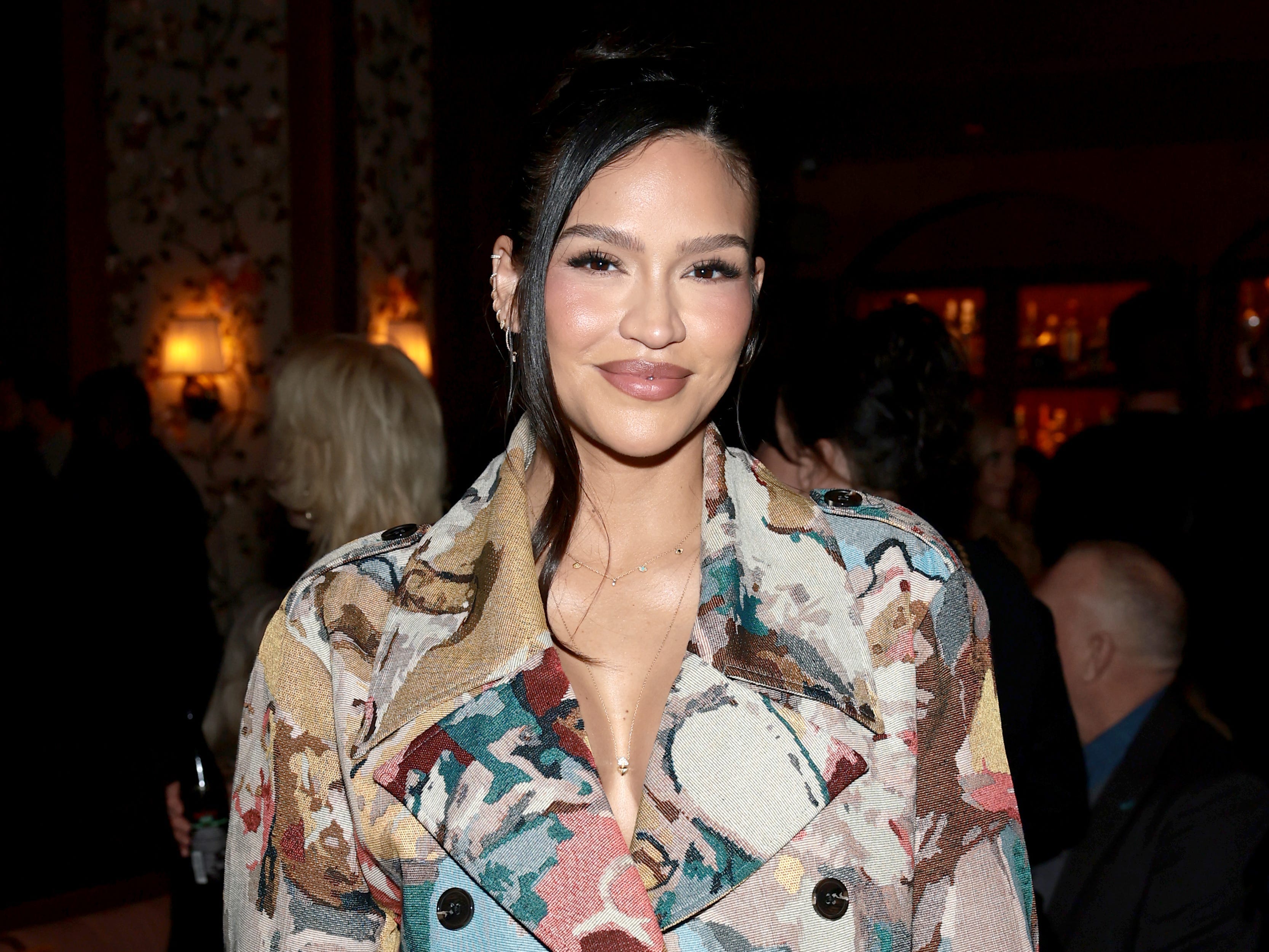 A woman wwearing a blue, pink, green, and beige dress that is styled like a double-breasted blazer.