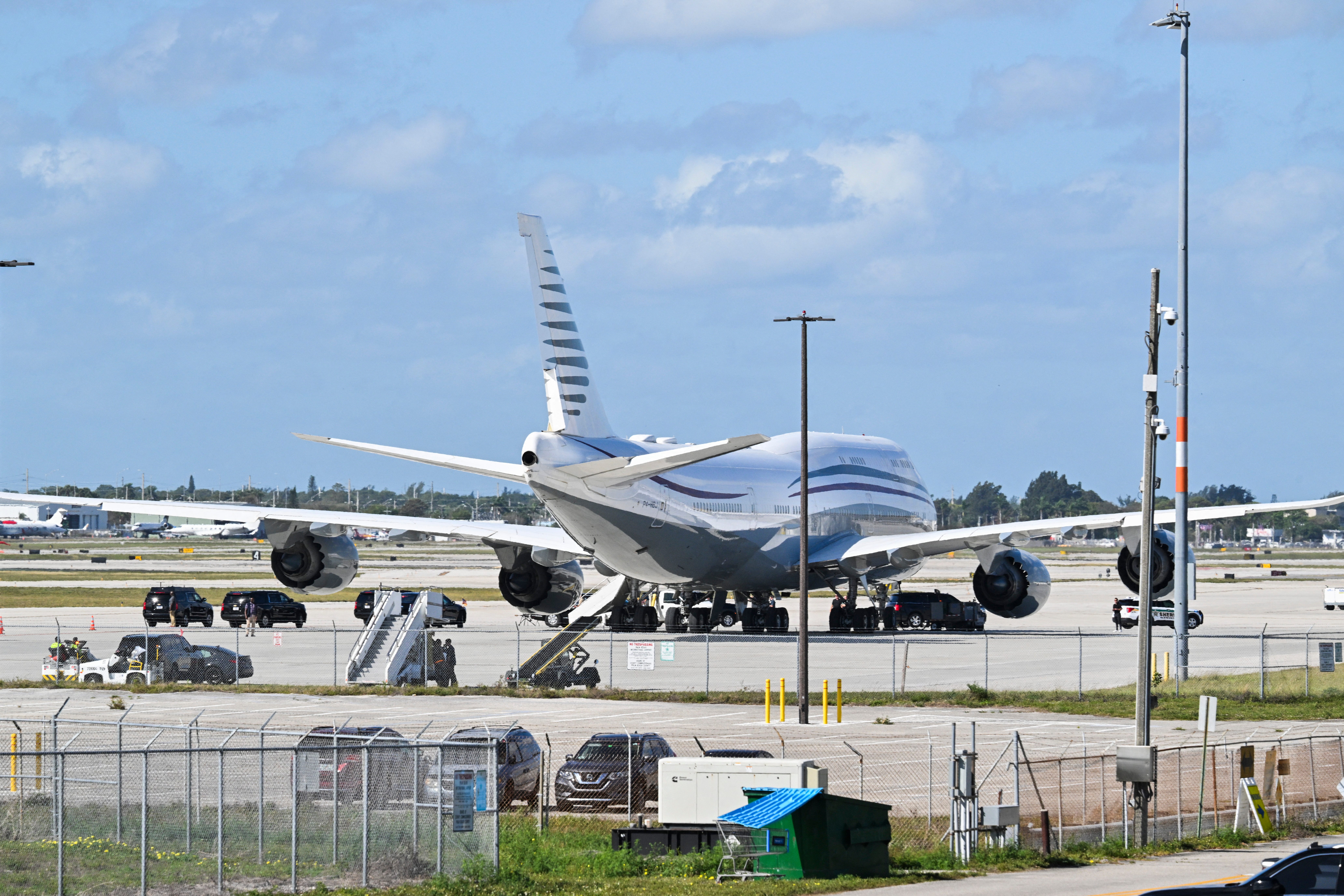 The motorcade of US President Donald Trump is parked next to a Qatari Boeing 747 on the tarmac of Palm Beach International Airport.