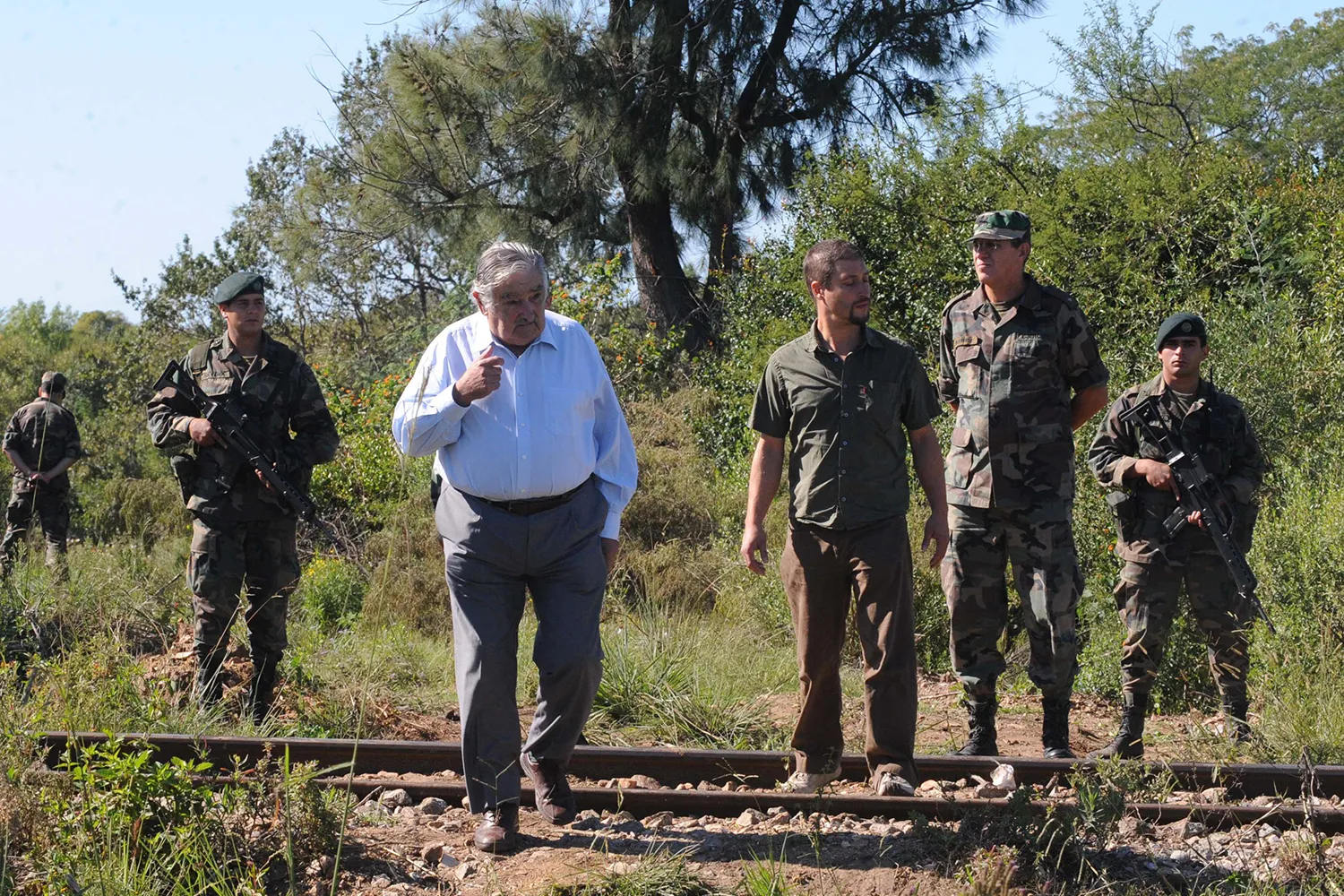 José Mujica walks with an anthropologist and soldiers.