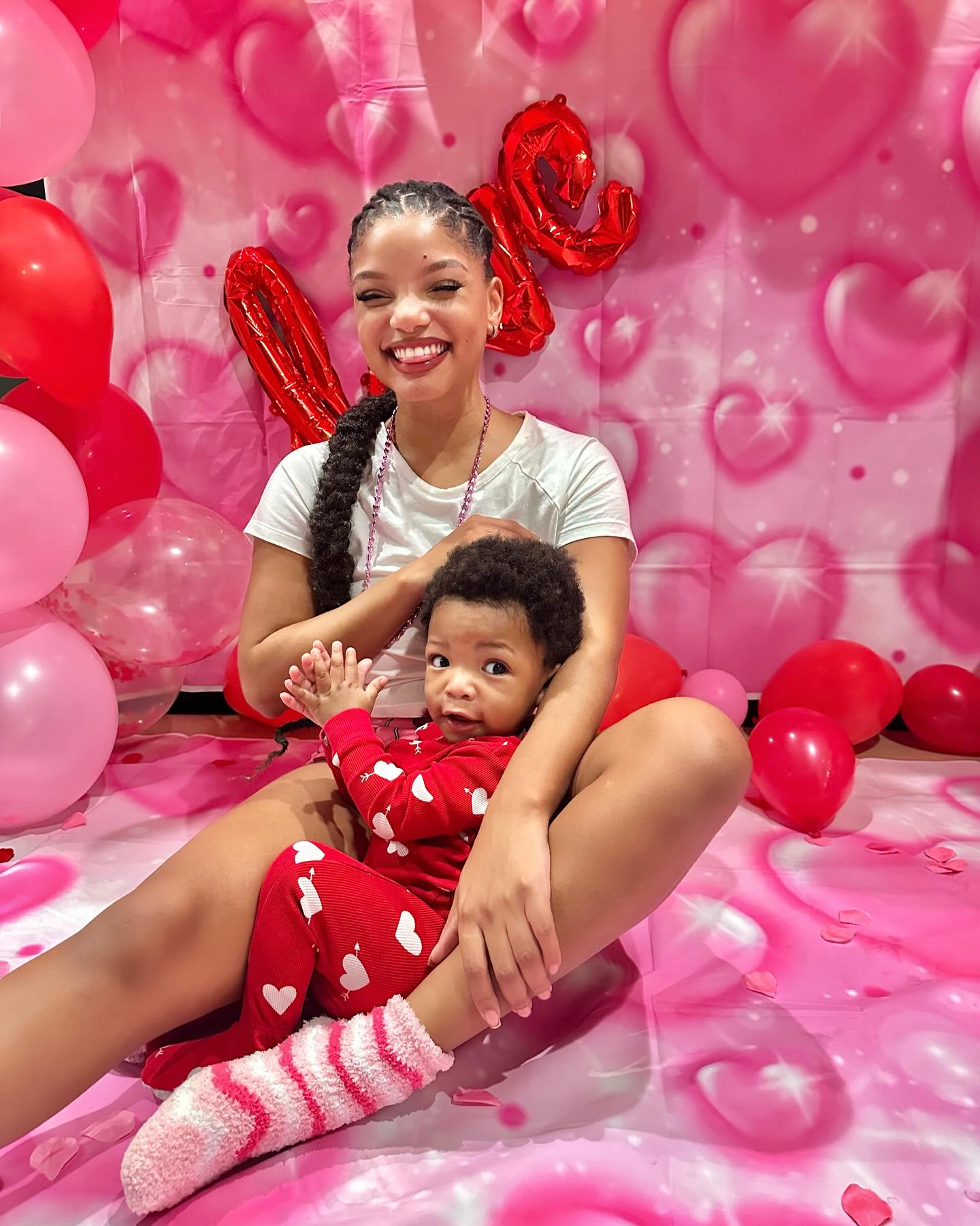 Halle Bailey and her son Halo surrounded by red and pink hearts. 