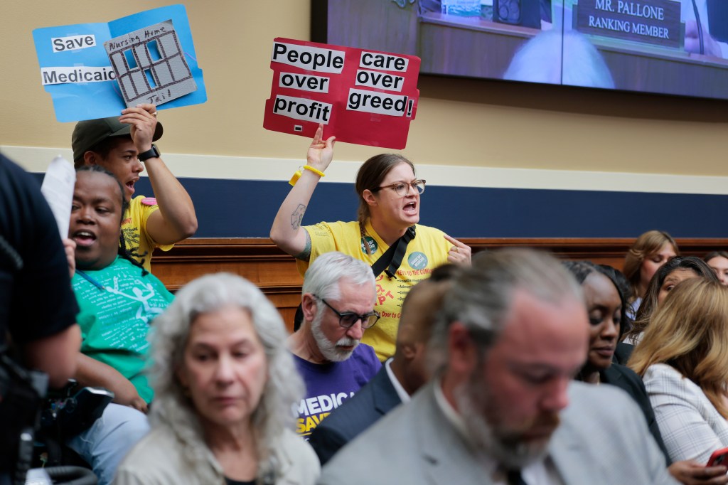 Protesters hold up signs inside of a markup meeting with the House Committee on Energy and Commerce committee on Capitol Hill on May 13, 2025 in Washington, DC.
