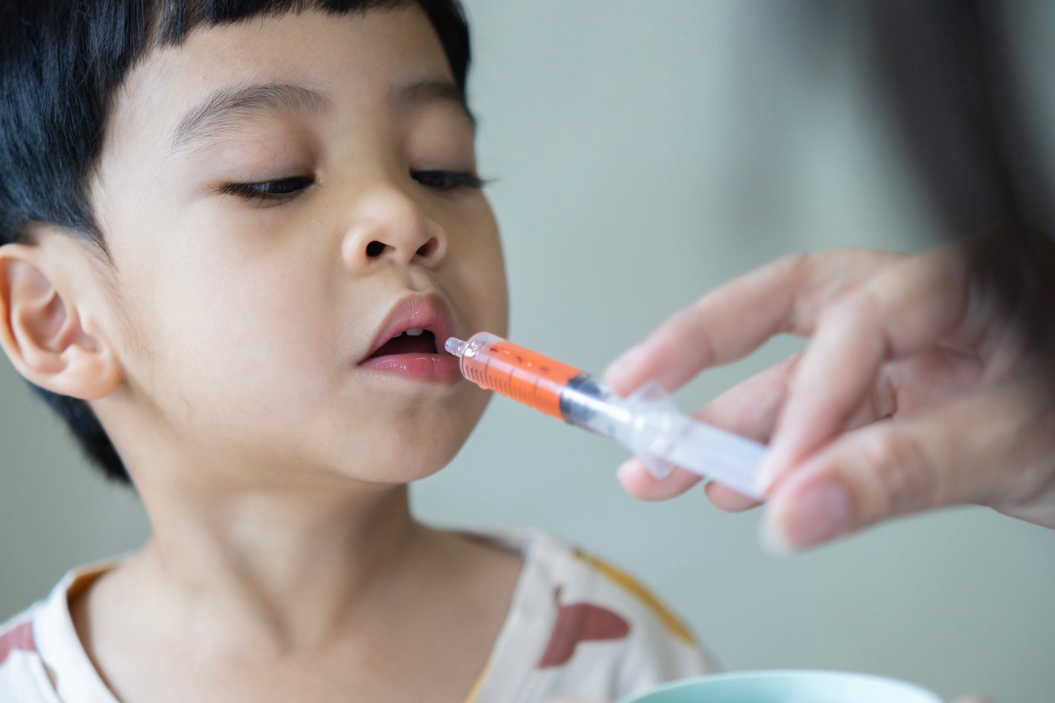 kid taking oral syringe medicine