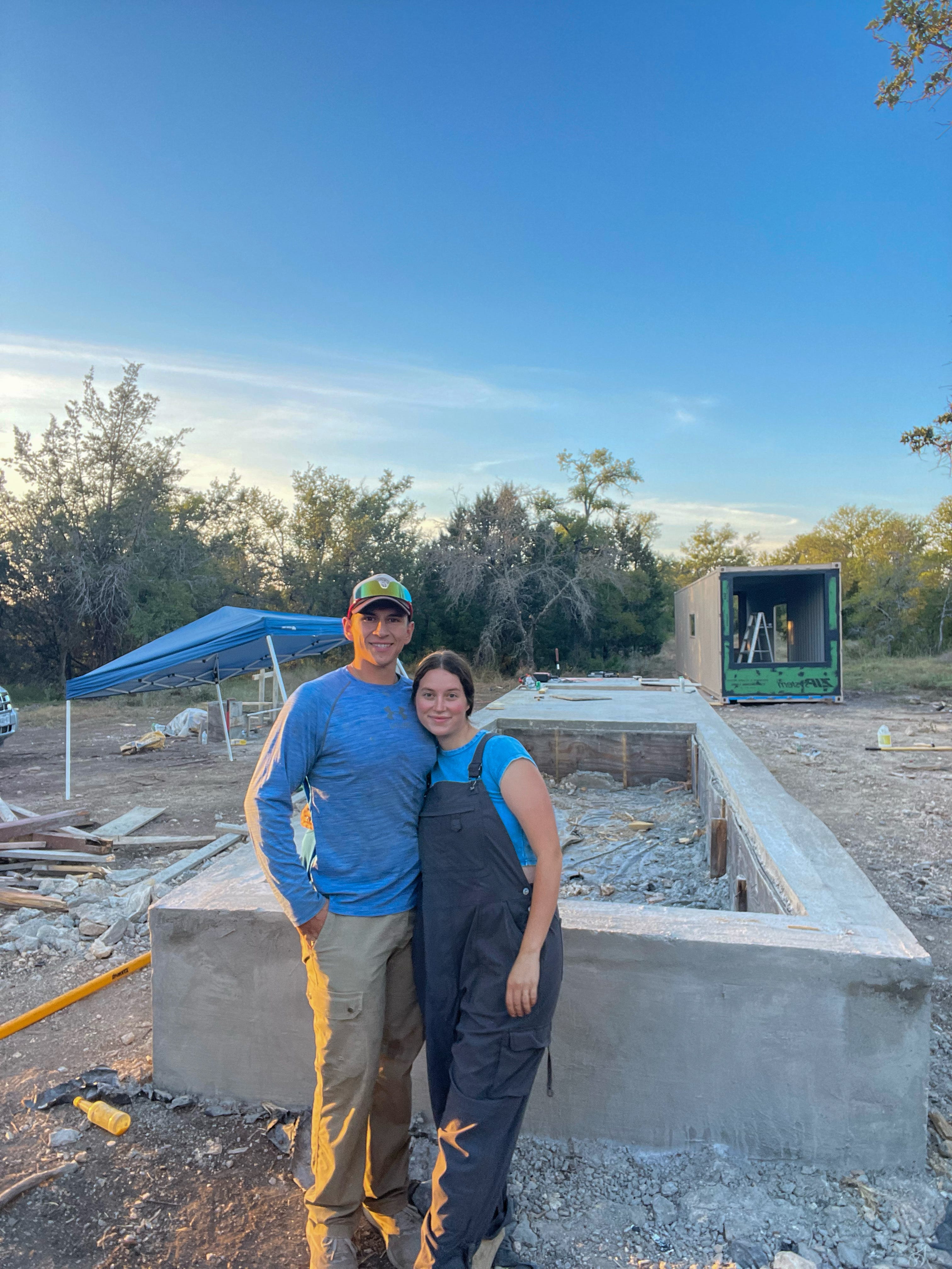 A couple stands together in front of a construction site.