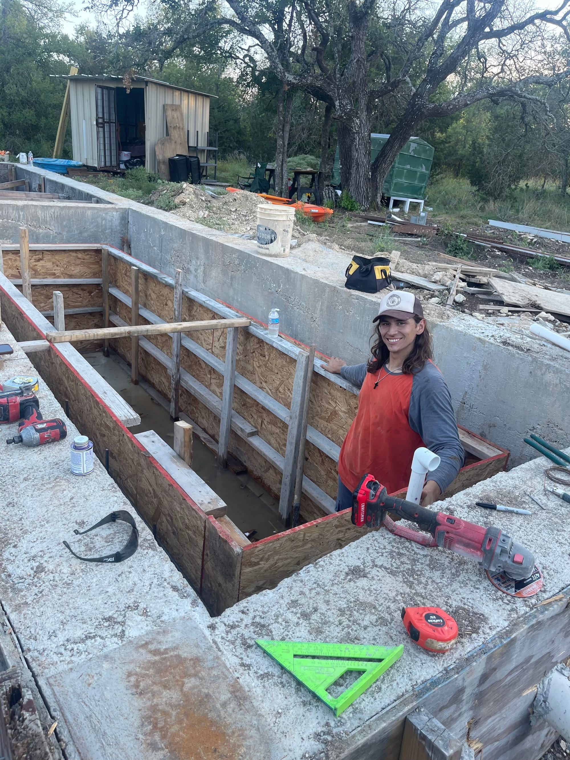 A man stands inside the foundation of a home.