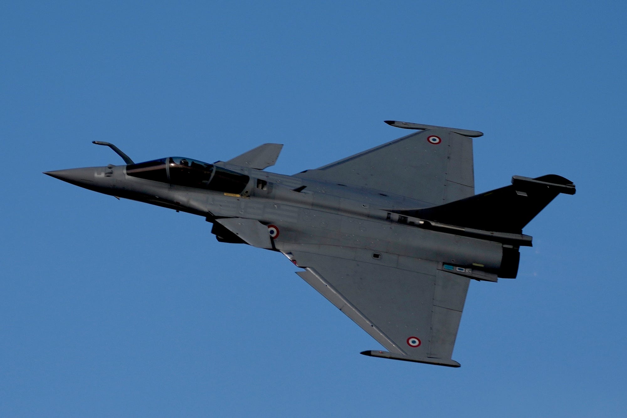 A dark gray jet in a blue sky
