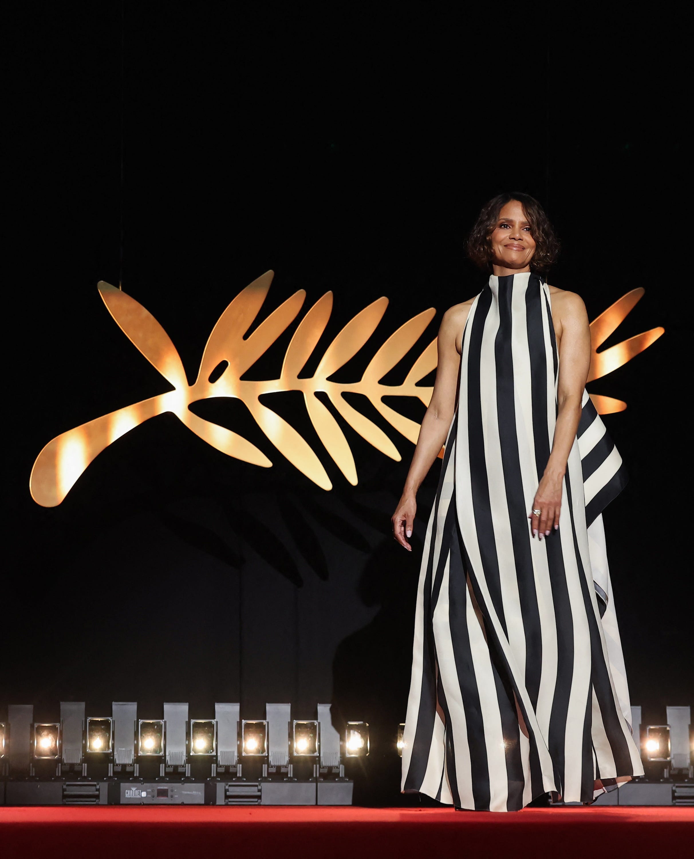 Halle Berry walks onstage in a black-and-white striped gown at the Cannes Film Festival.