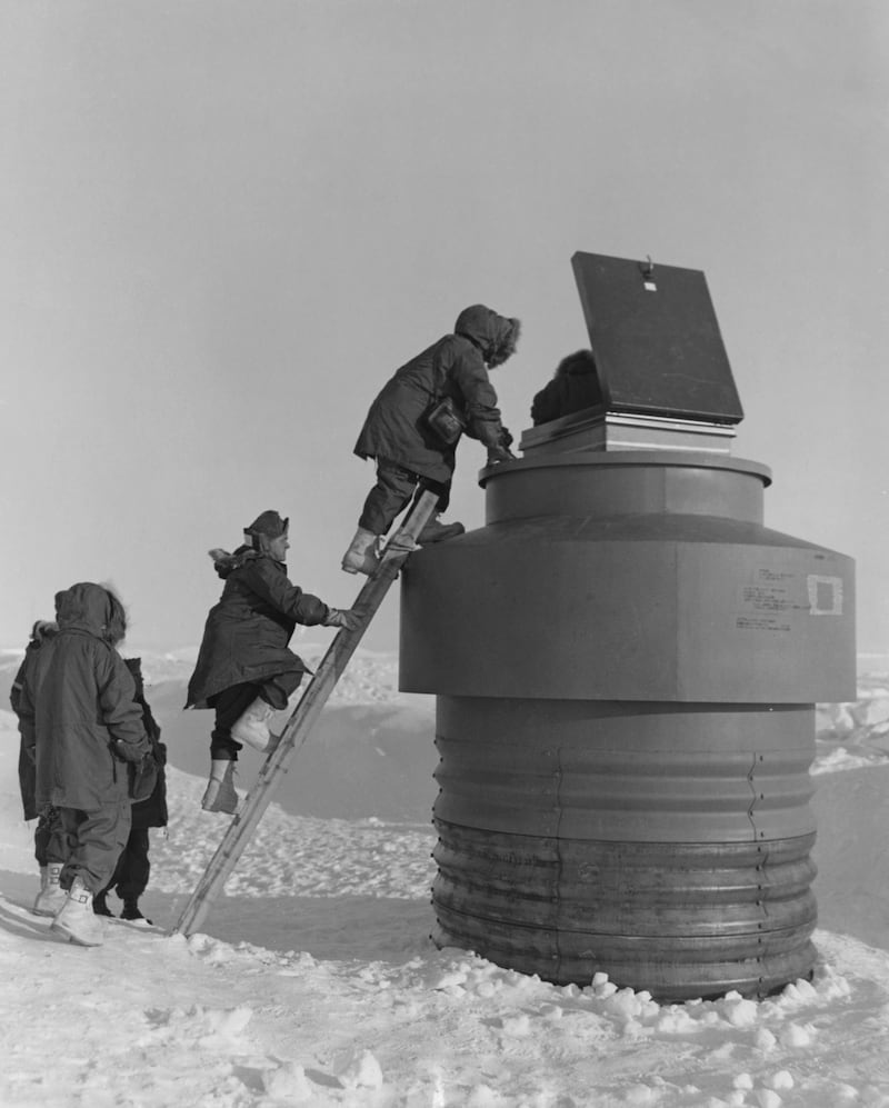U.S. military personnel climb up to an escape hatch to enter Camp Century in June 1959.