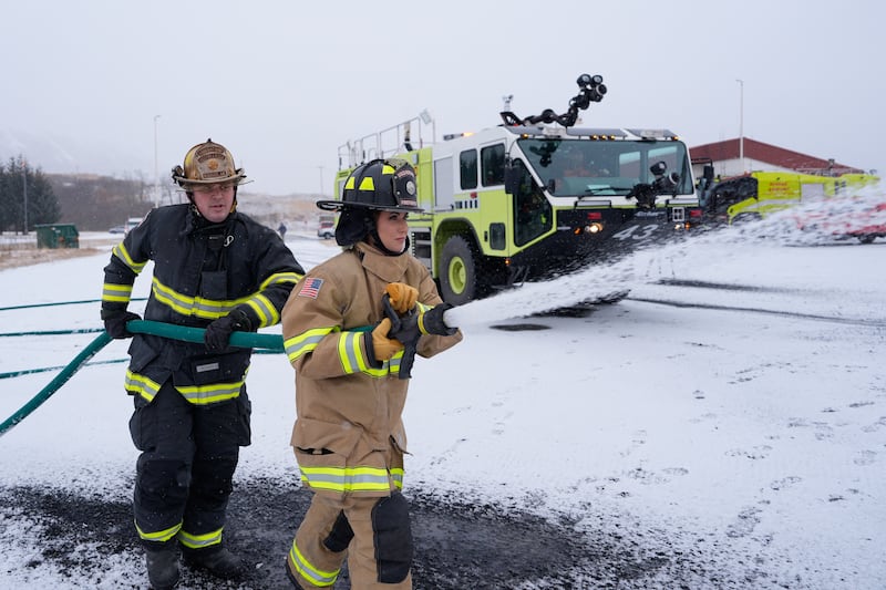US Homeland Security Secretary Kristi Noem (R), participates in a firefighting drill with a training helicopter during a tour of US Coast Guard Air Station Kodiak, March 17, 2025, in Kodiak, Alaska.