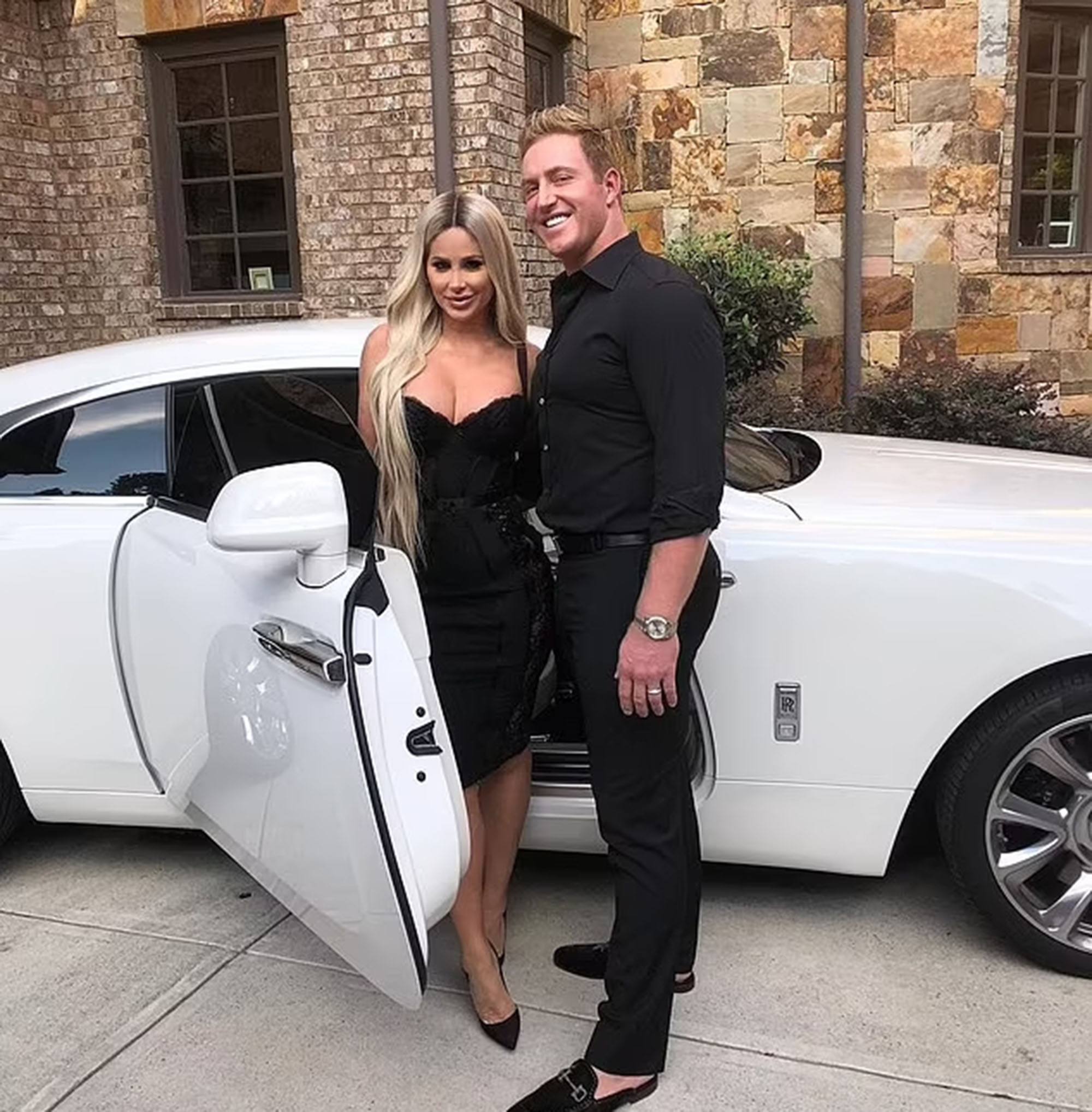 Kim Zolciak and Kroy Biermann standing by a white luxury car. 