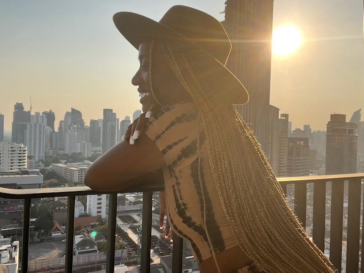 A woman posing on her balcony against the Bagnkok skyline.