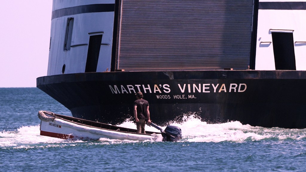 A man travels in a boat behind the Martha's Vineyard Ferry.