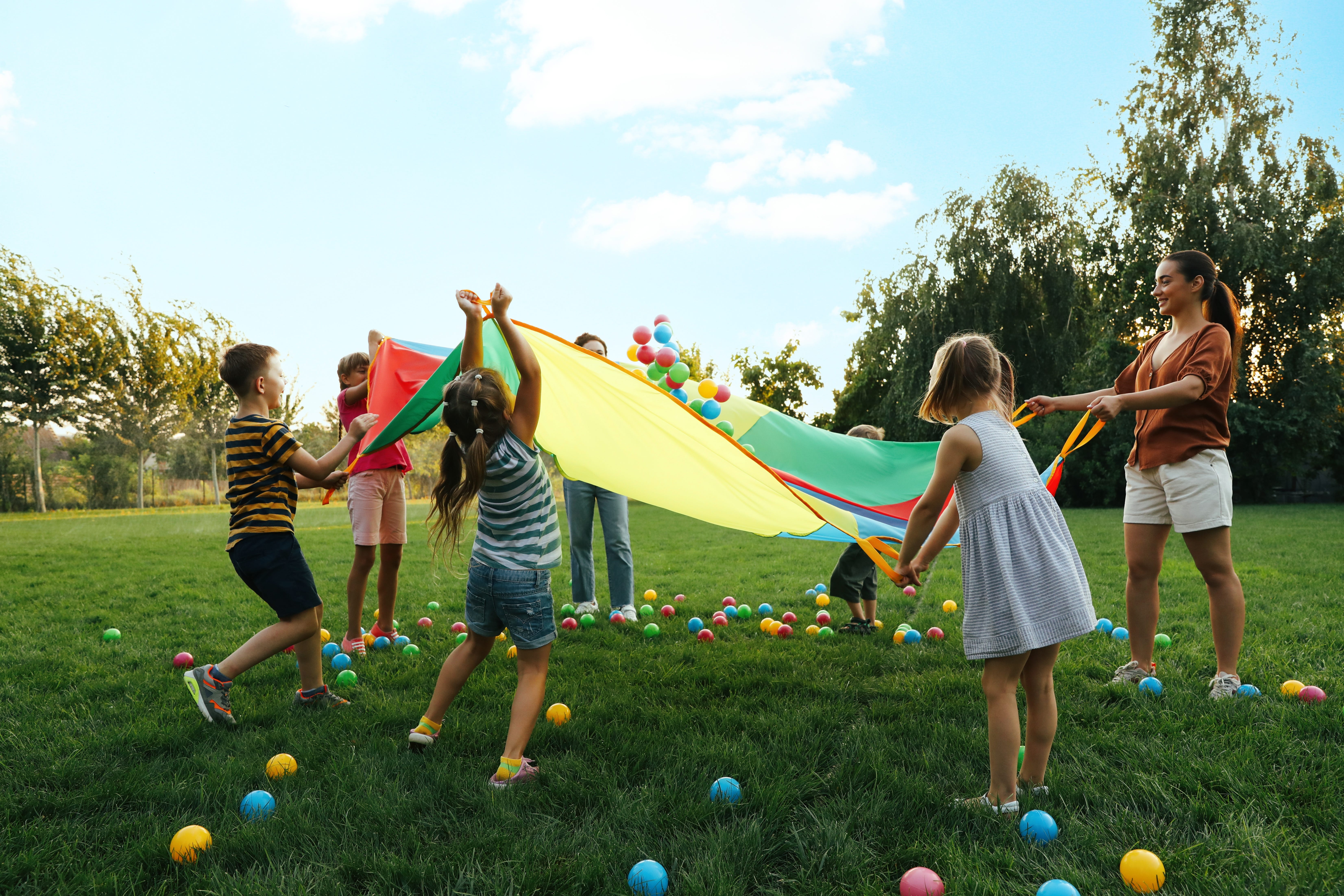 Kids playing with colorful parachute with an adult