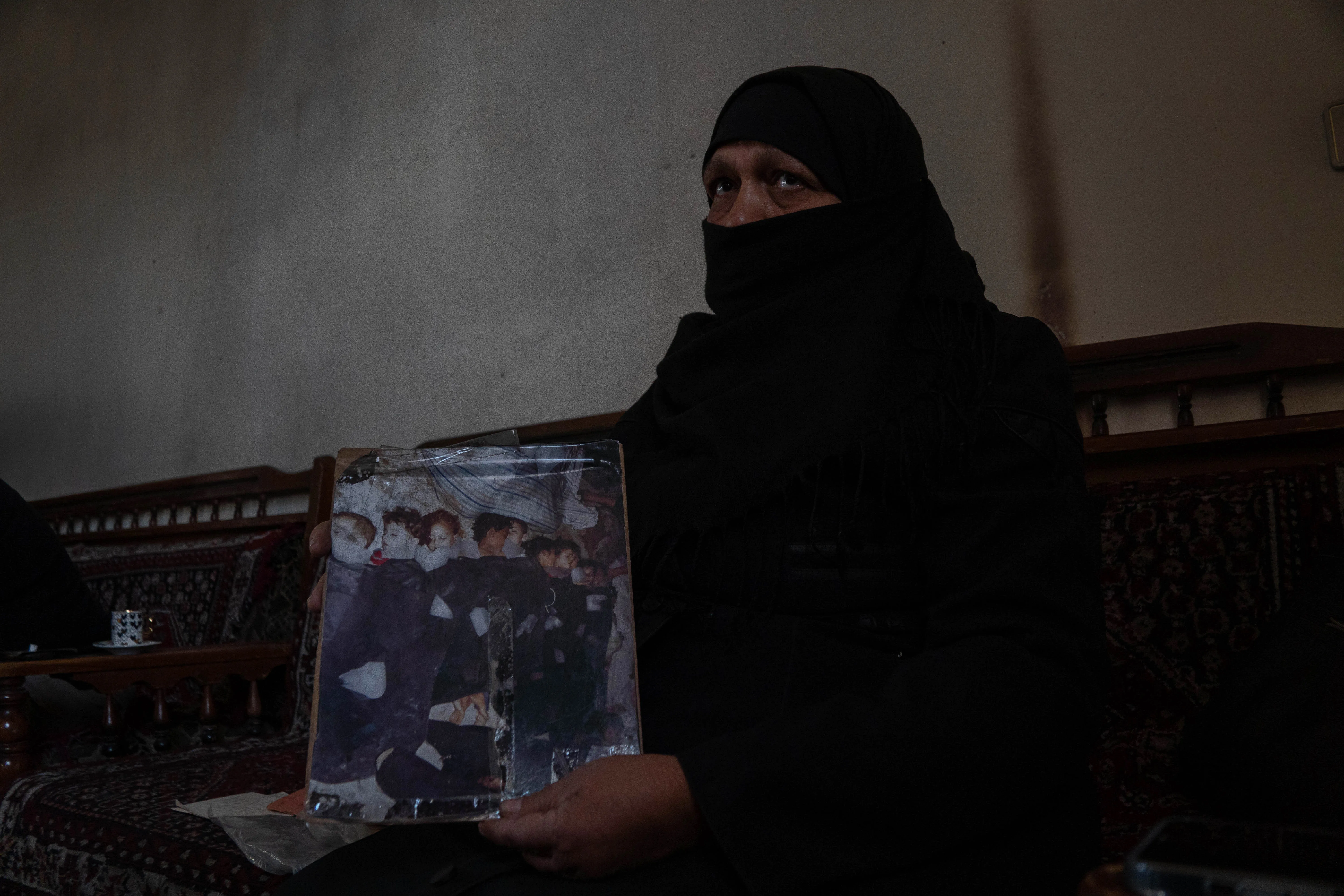 Um Mohammed holds up a photo at her house in Zamalka showing her grandchildren among those killed in chemical weapons attacks in 2013.