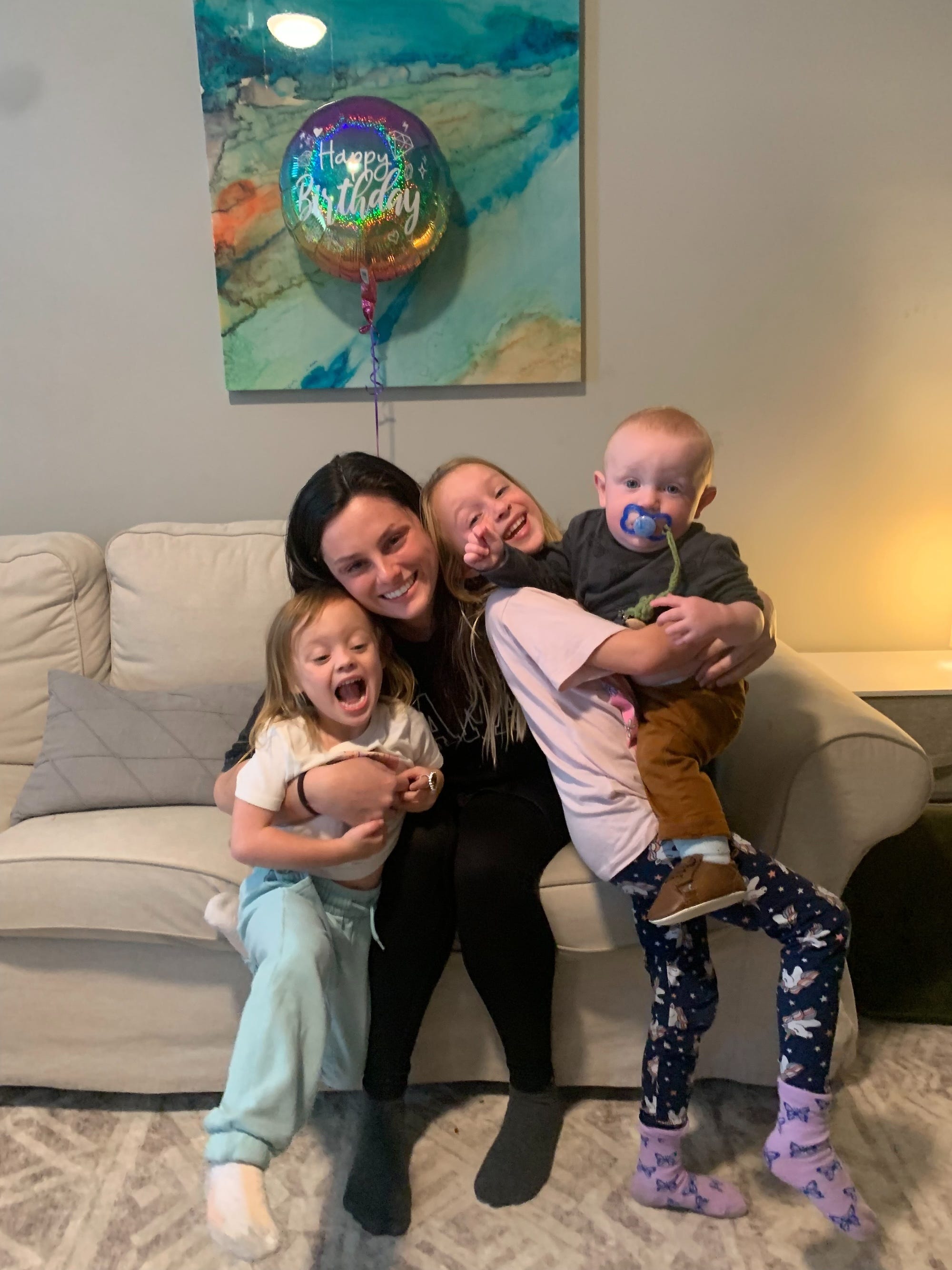 A woman smiles with three children.