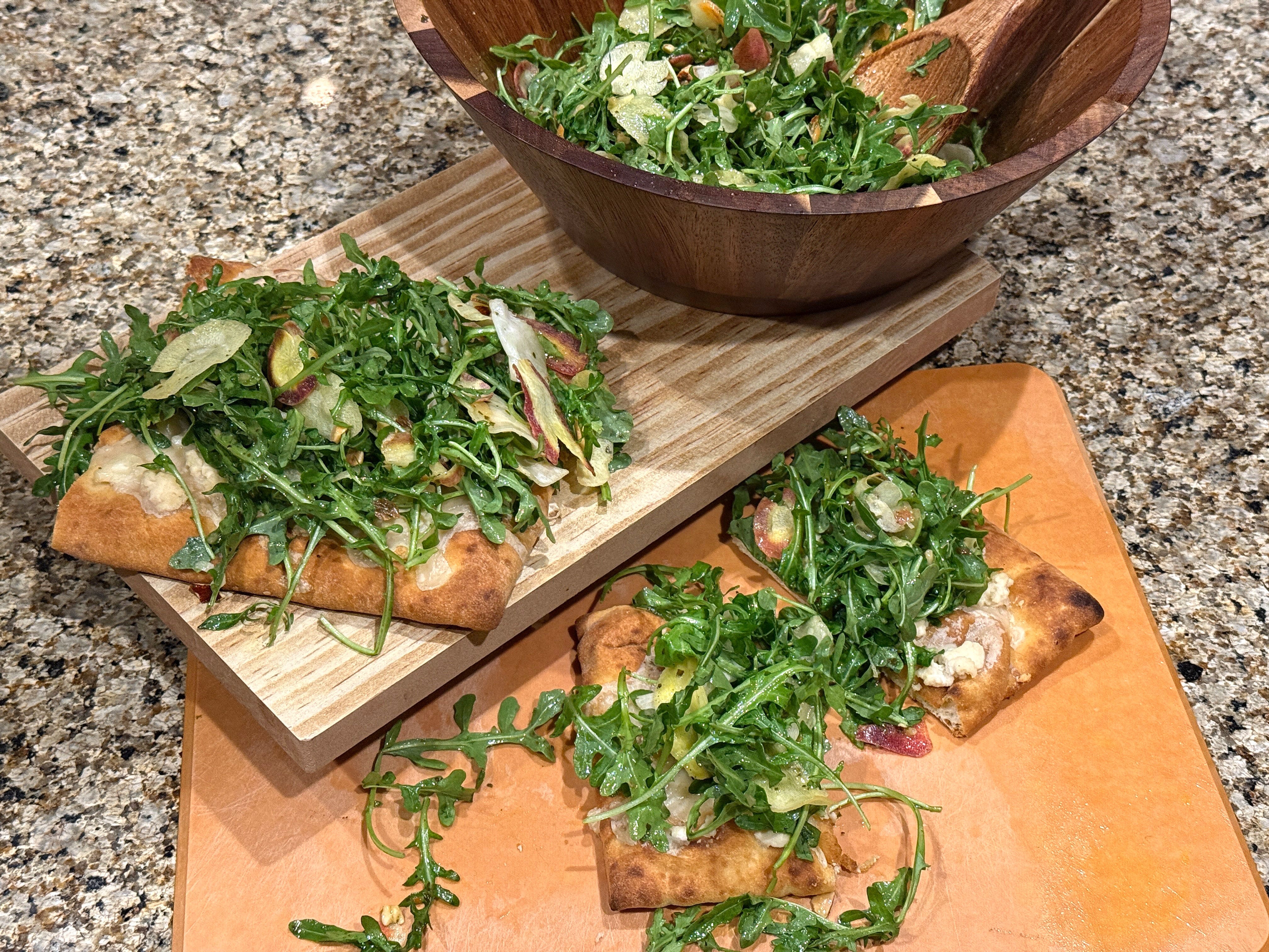 A large bowl of salad and three pieces of flatbread covered in greens.
