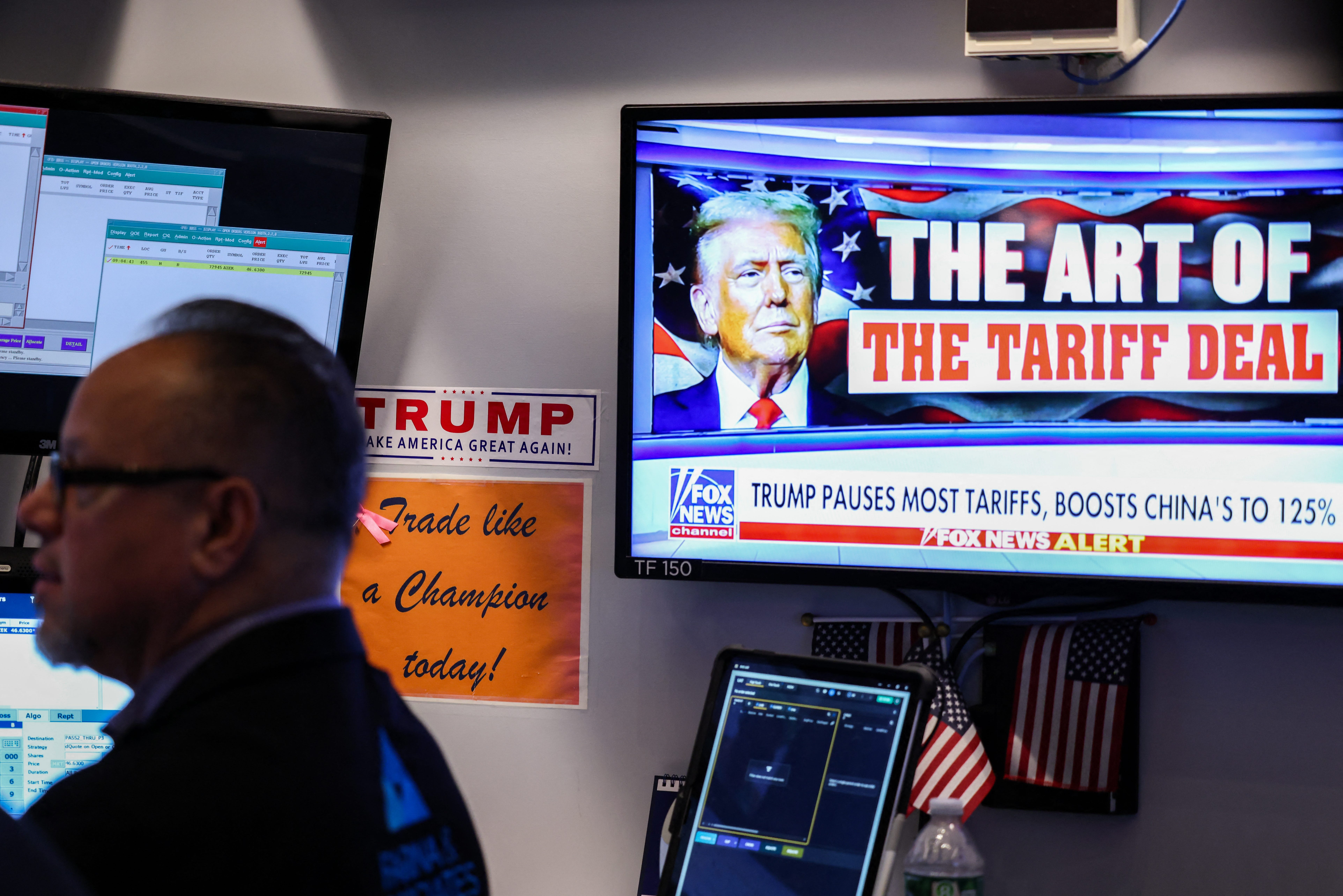 A trader works as a television screen shows news about US President Donald Trump's trade and tariff policies, on the floor of the New York Stock Exchange (NYSE) at the opening bell on April 10, 2025, in New York City.