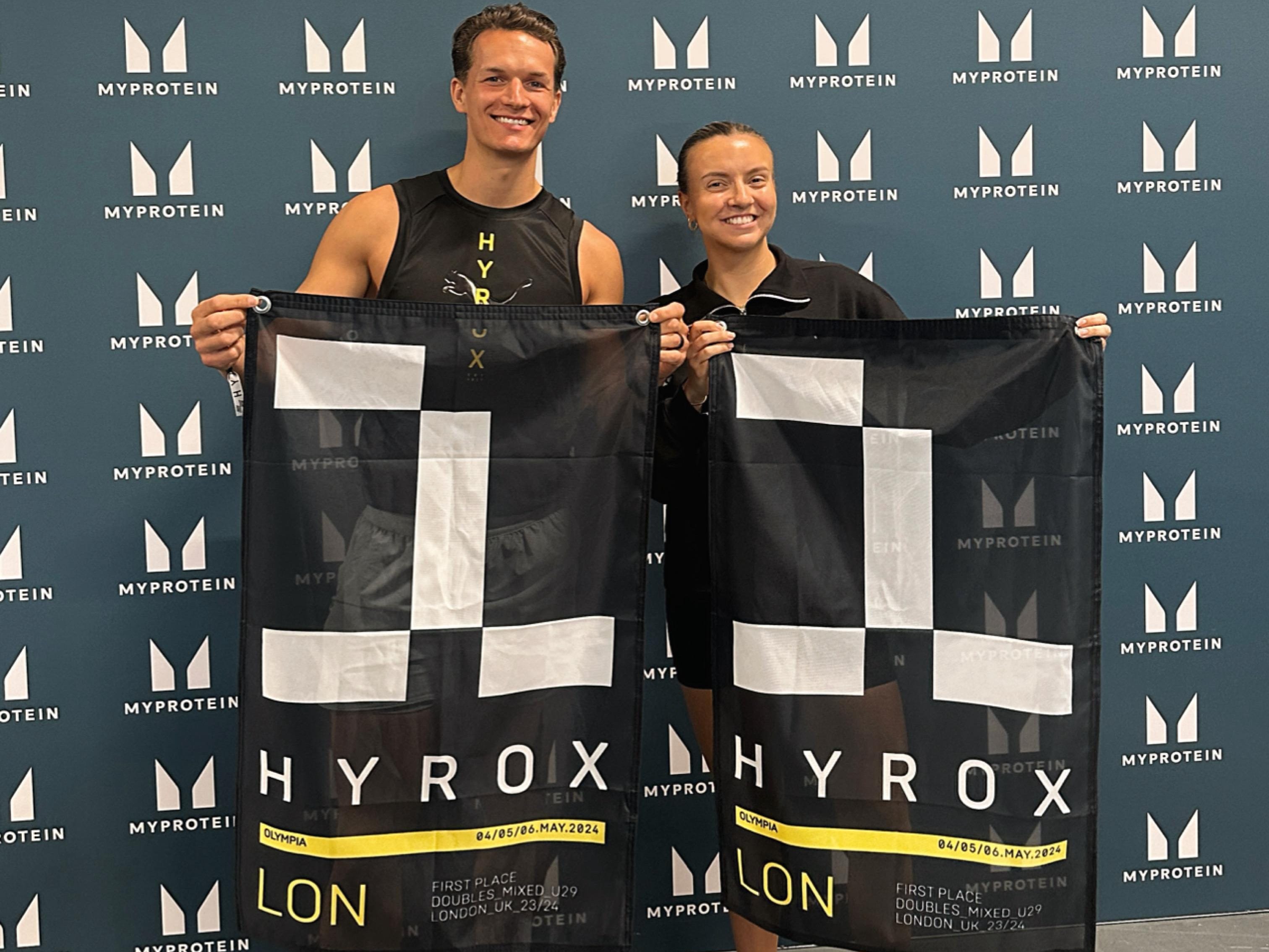 Danny Rae and Zoe Hague holding Hyrox flags