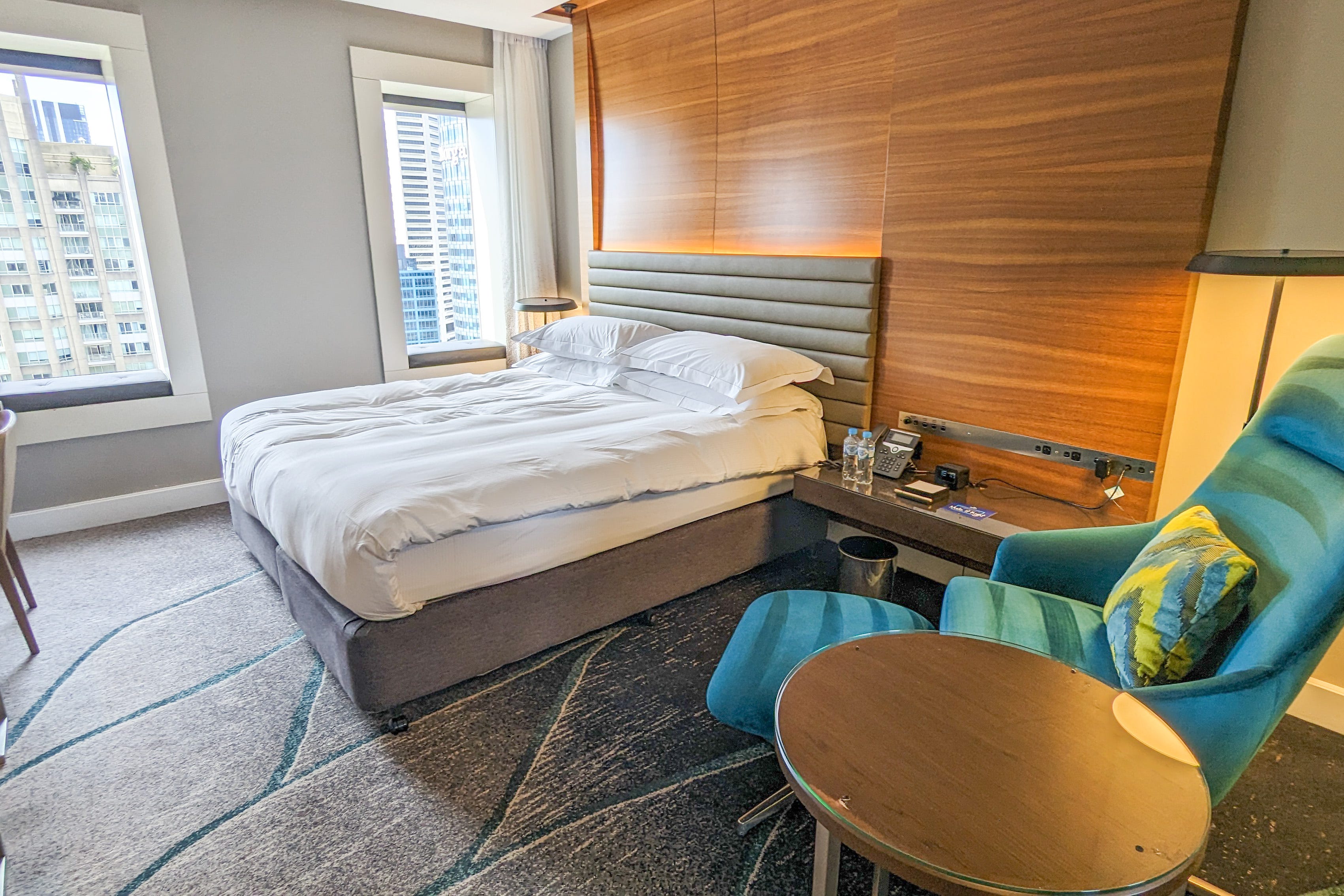 A hotel room with wood wall behind the bed