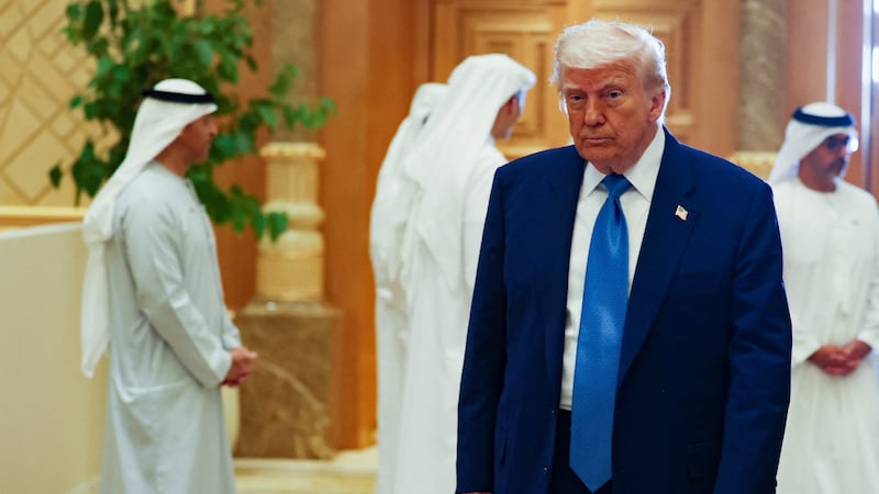 President Donald Trump stands in front of men wearing traditional Emirati attire during visit to UAE.