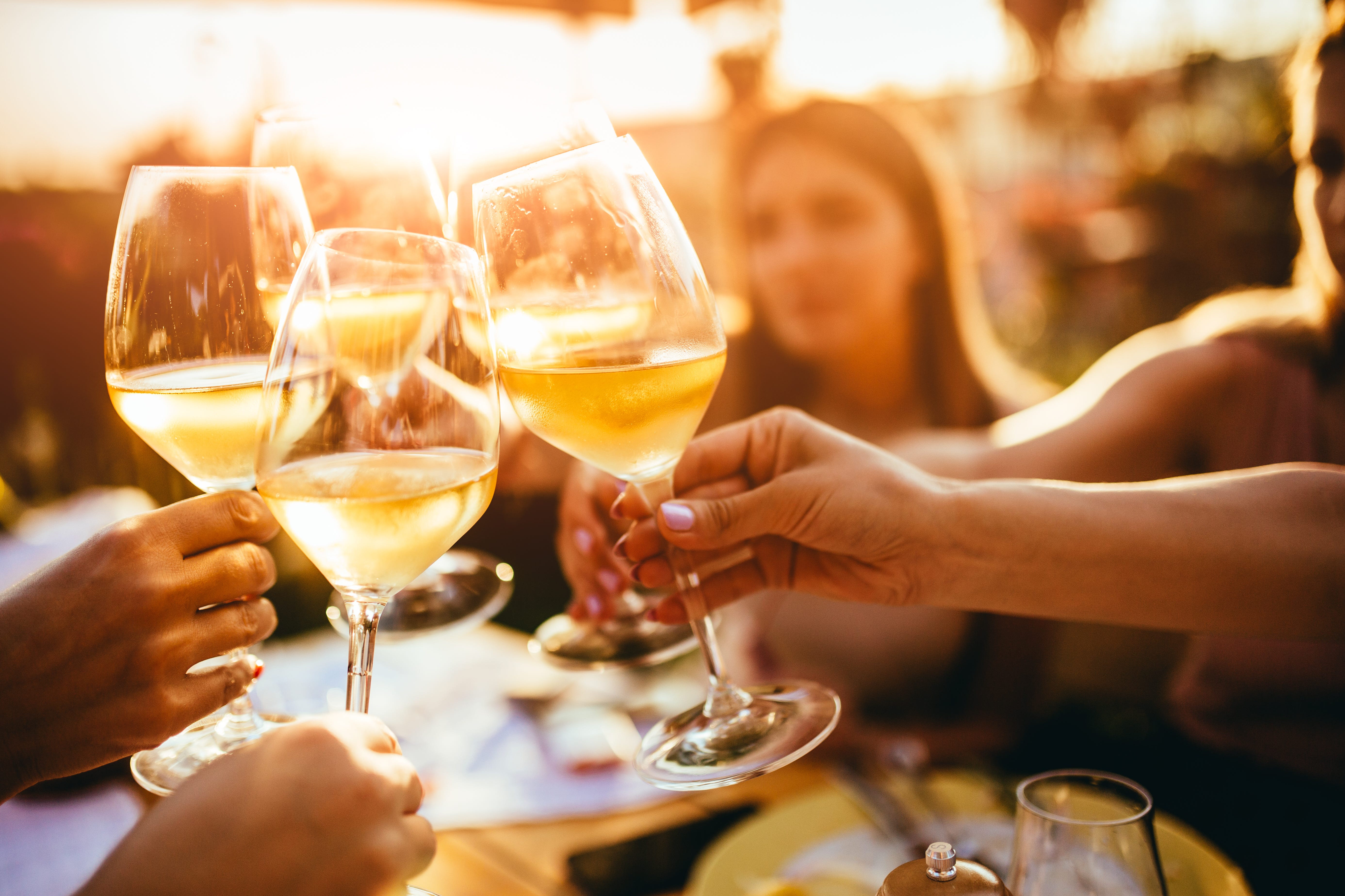 People clinking glasses of white wine together.