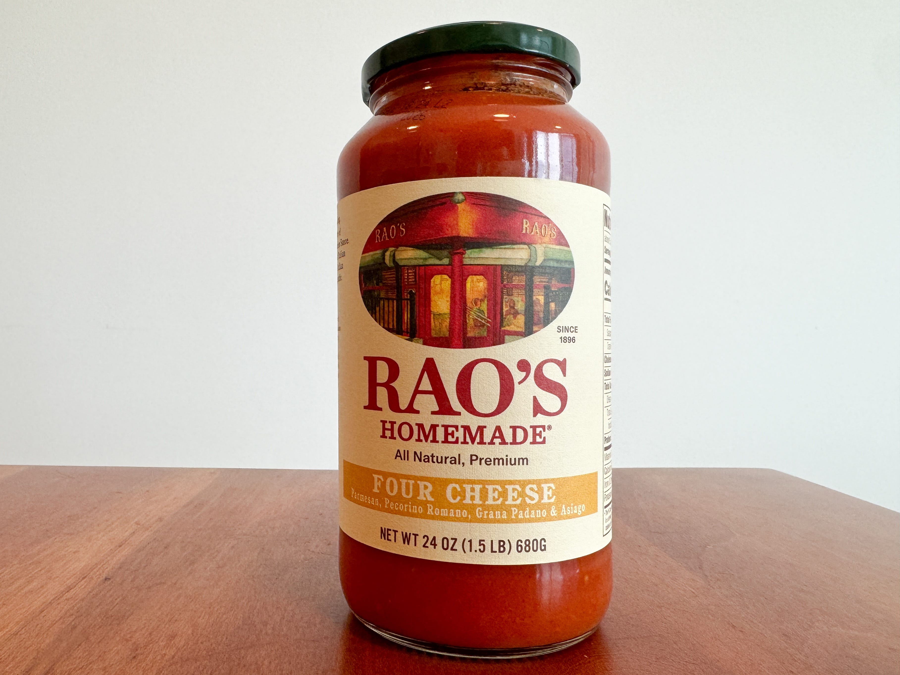 A jar of Rao's Homemade four-cheese pasta sauce on a wooden table.