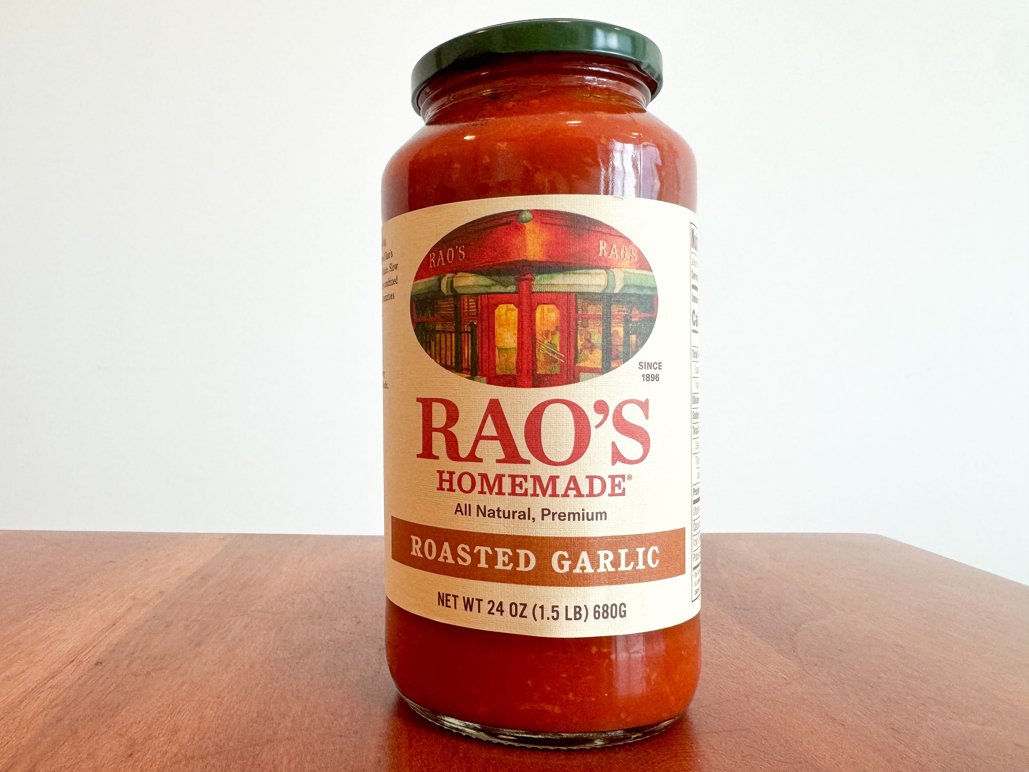 A jar of Rao's Homemade roasted-garlic pasta sauce on a wooden table.