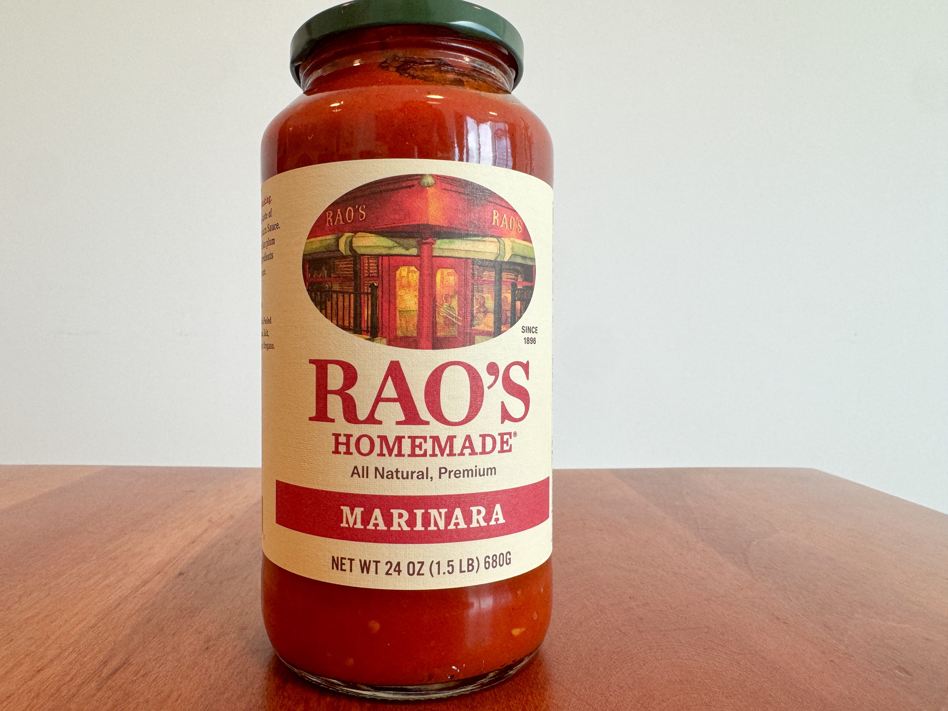A jar of Rao's Homemade marinara sauce on a wooden table.