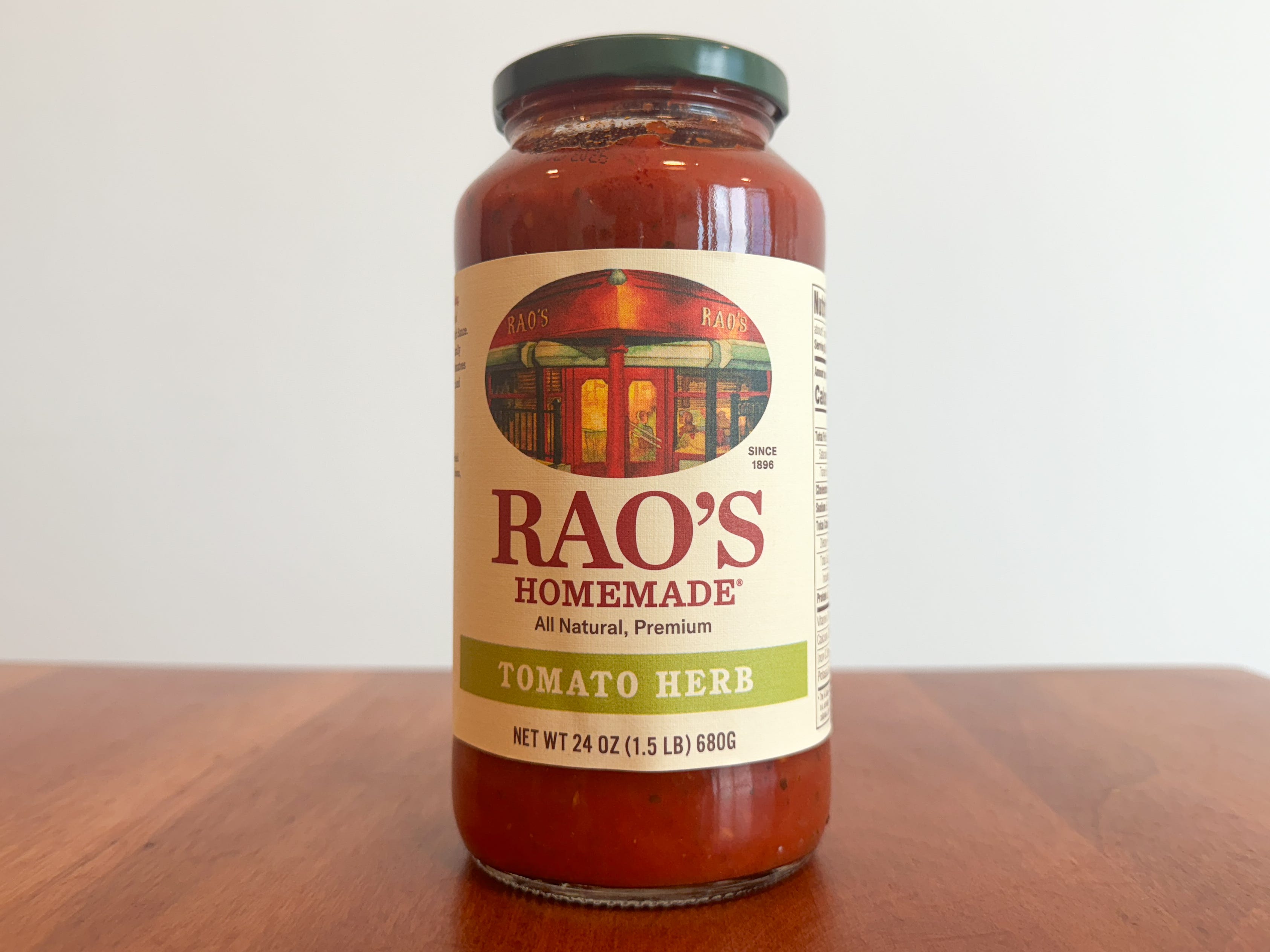 A jar of Rao's Homemade tomato-basil pasta sauce on a wooden table.