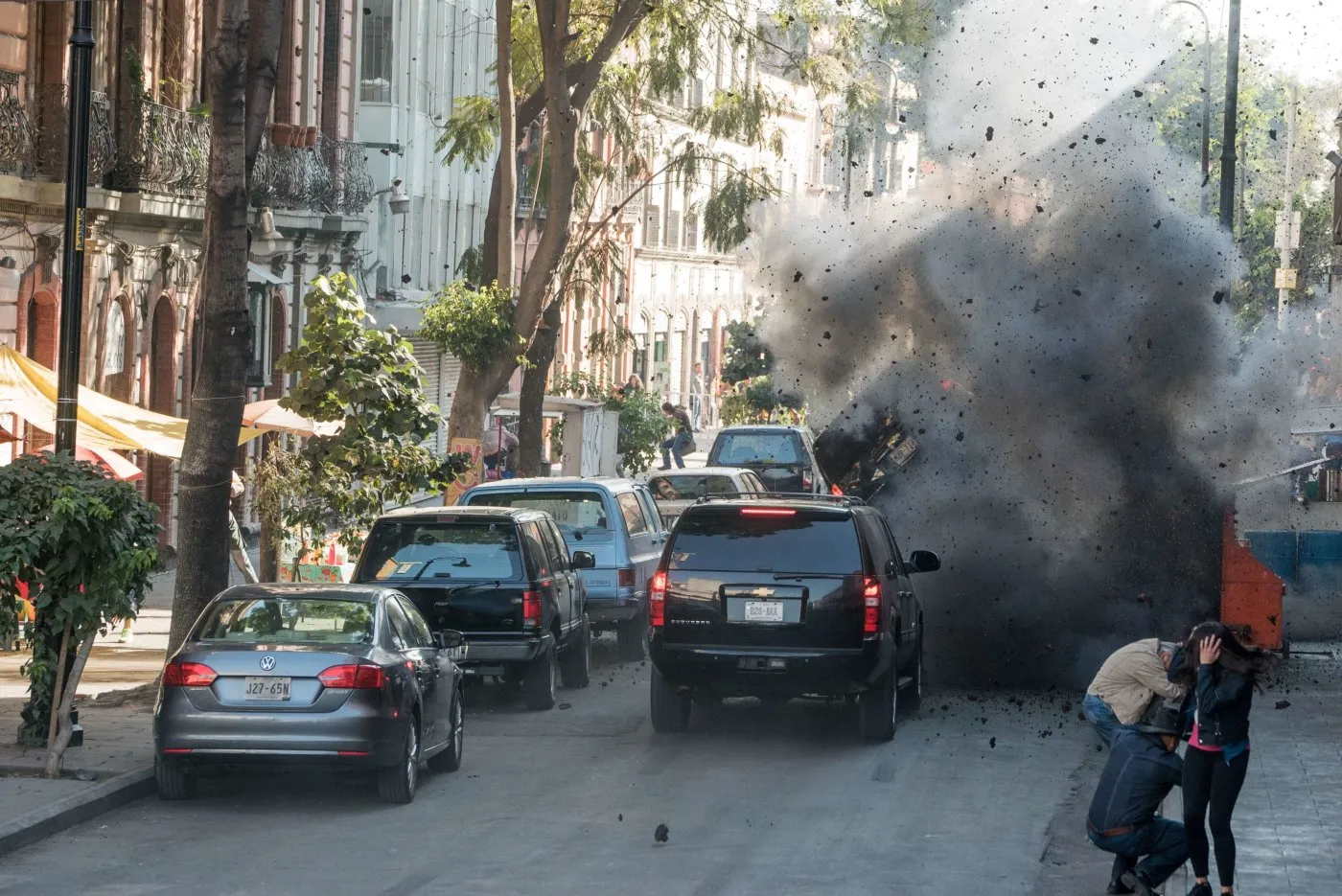 An explosion sends smoke over a line of cars on a city street.