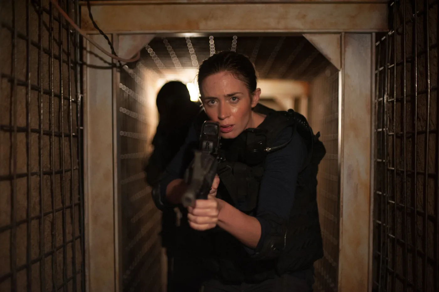 A woman with a gun drawn patrols inside a tunnel.