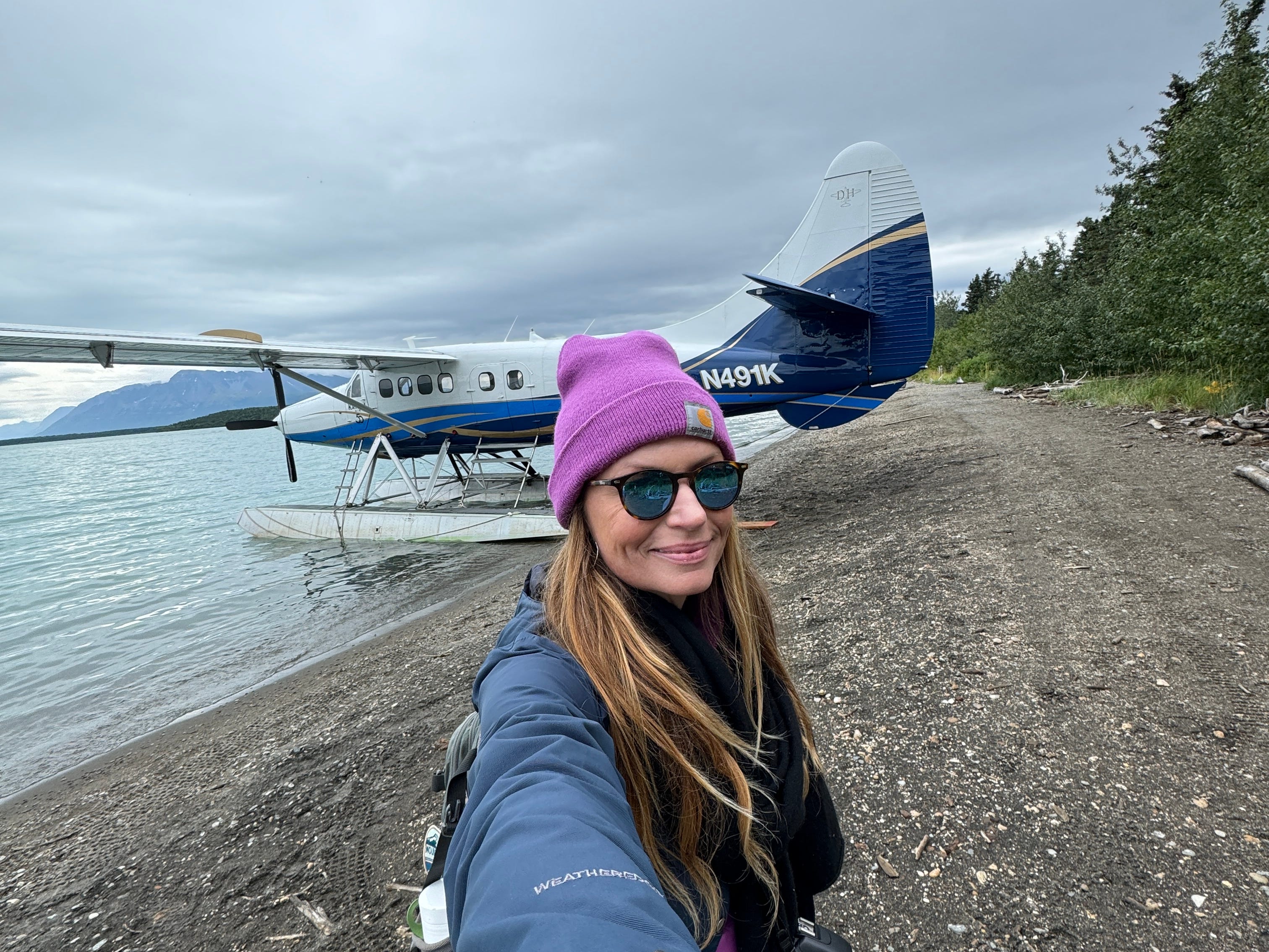 The author takes a selfie in front of a small plane on a beach.