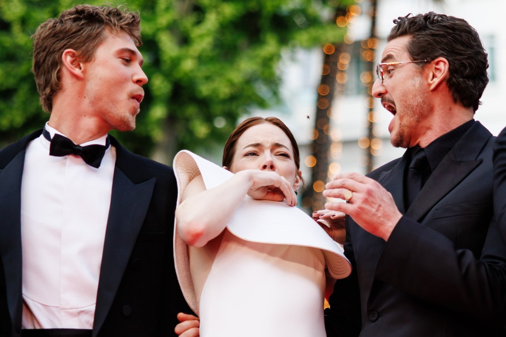 Emma Stone being attacked by a bee while posing with Austin Butler and Pedro Pascal at the Cannes Film Festival Friday. 