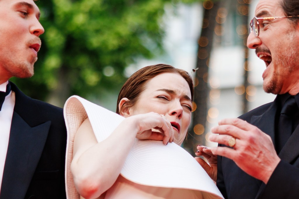 Emma Stone being attacked by a bee while posing with Austin Butler and Pedro Pascal at the Cannes Film Festival Friday. 