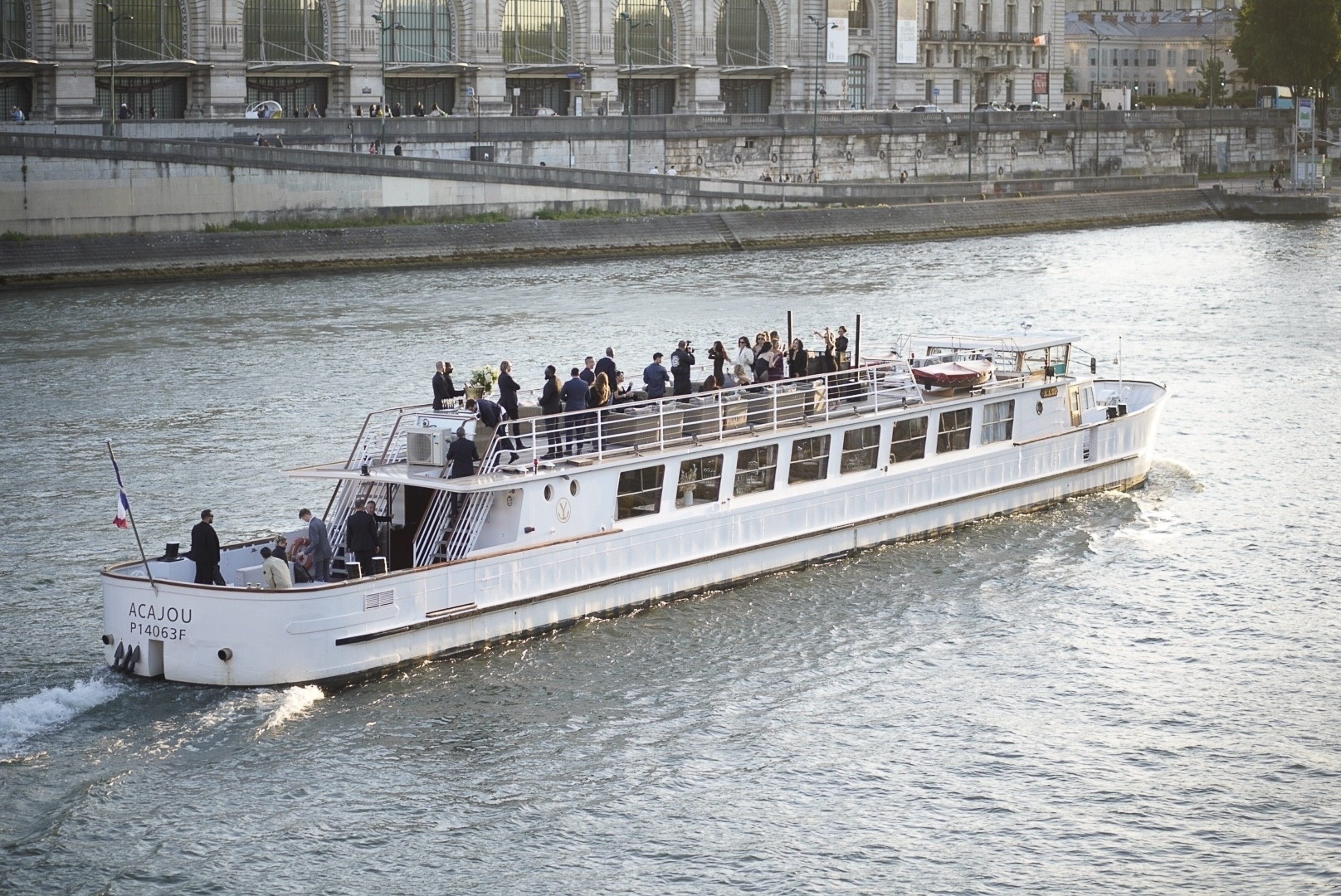 A white boat with guests on the Seine. 