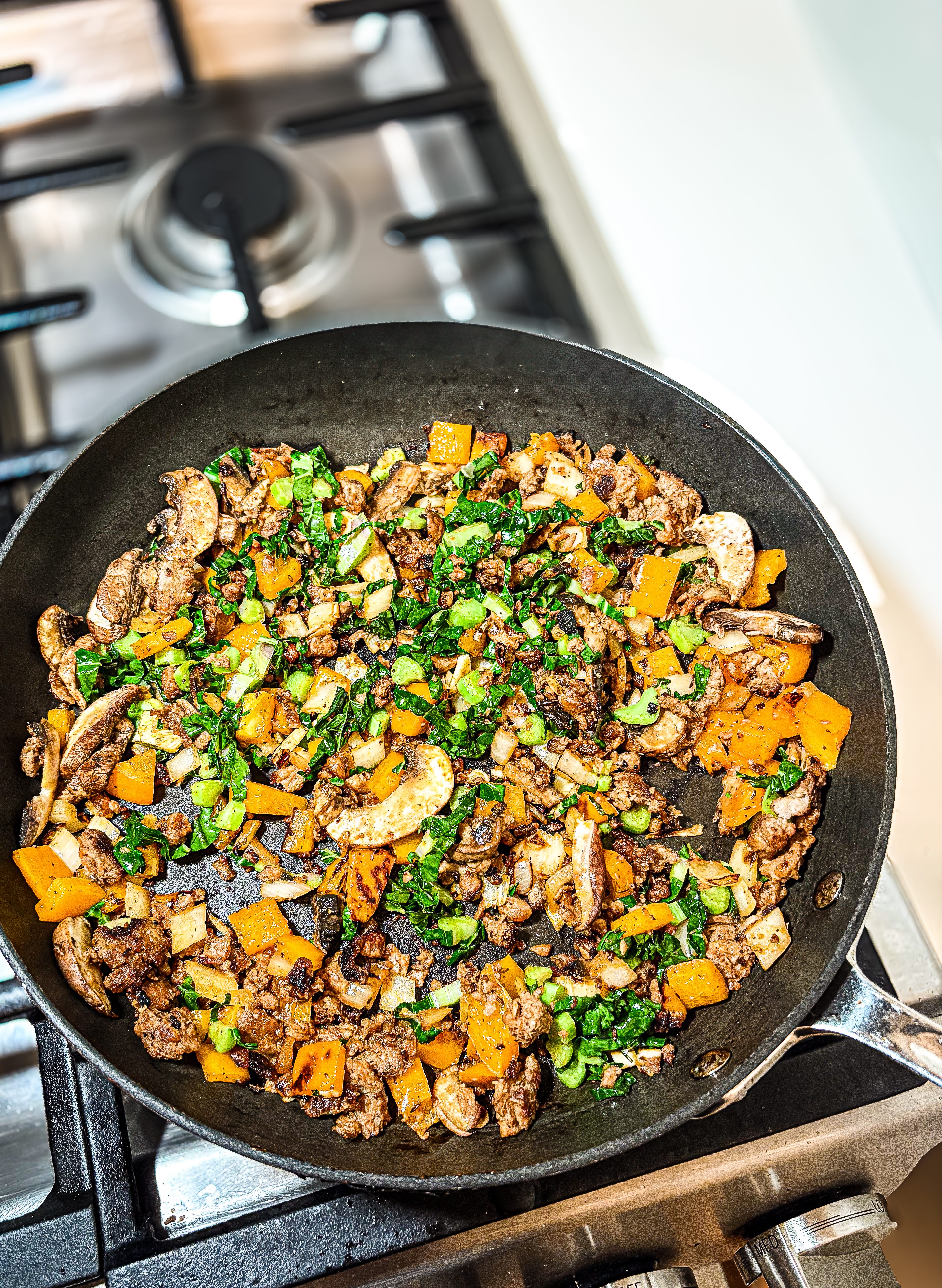 Stir fry over a stove with mushrooms and greens