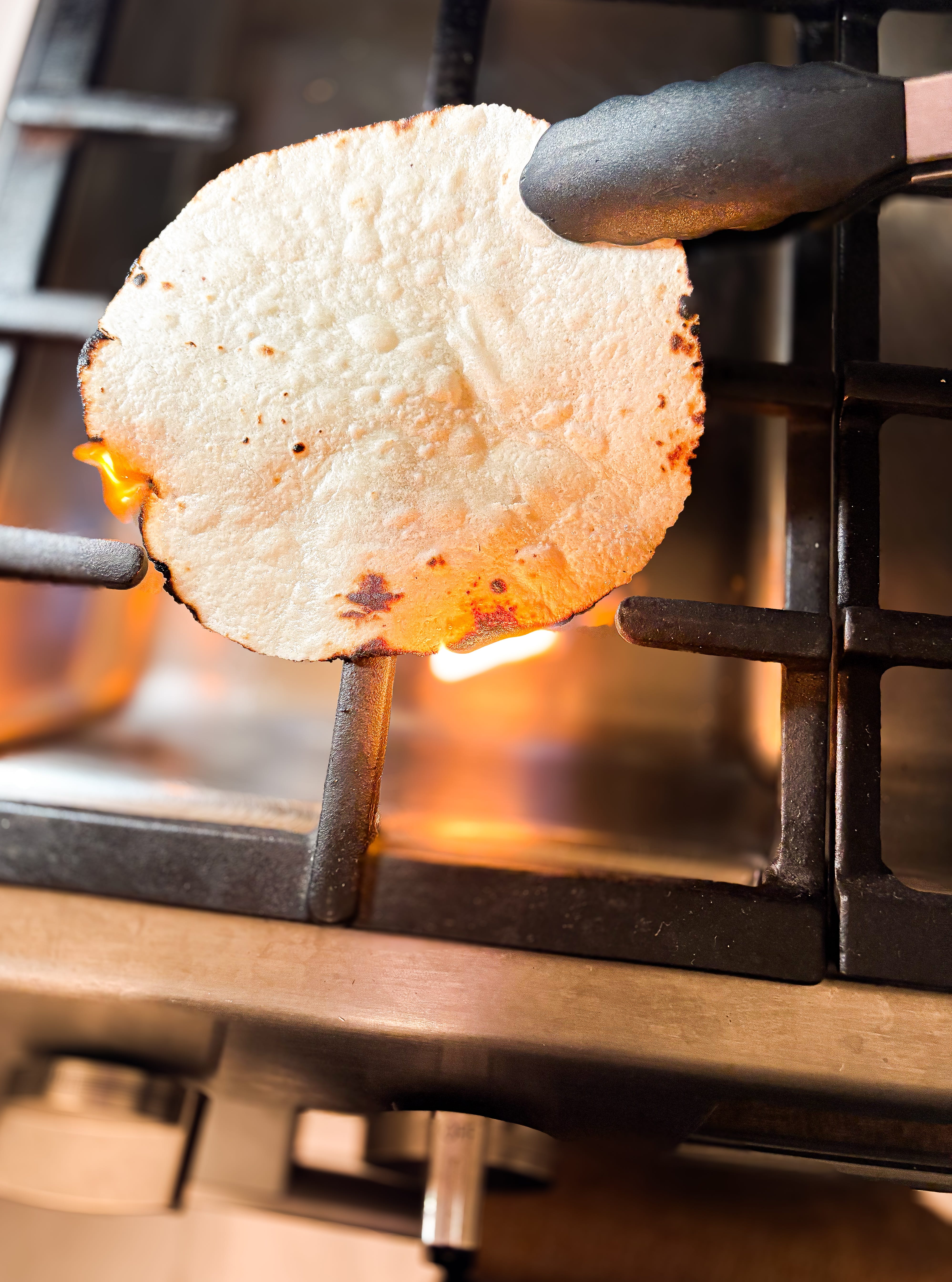 Tortilla roasted over open flame on gas stove