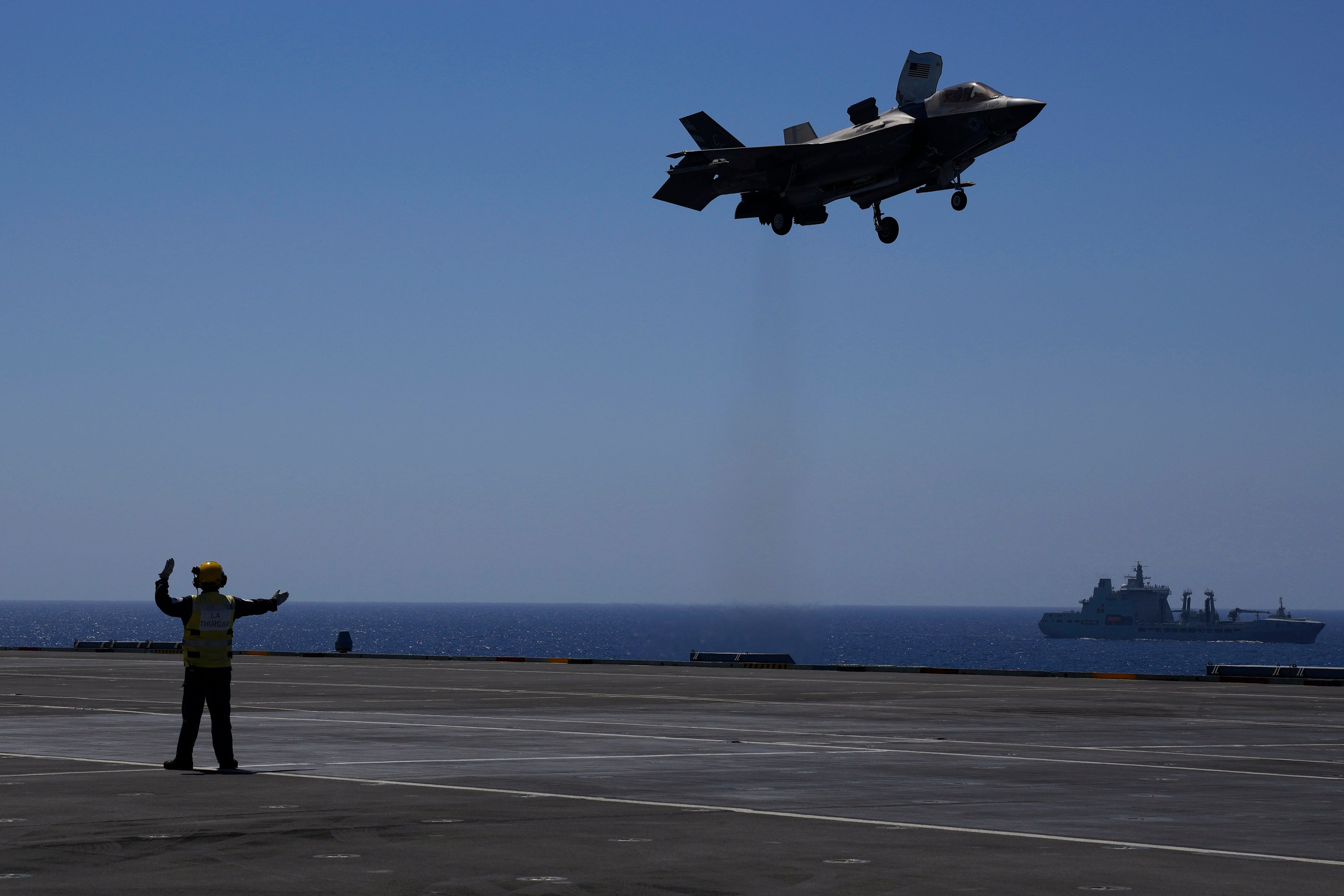 A crew member makes a signal to F-35 aircraft for landing on the U.K.'s aircraft carrier HMS Queen Elizabeth in the Mediterranean Sea on Sunday, June 20, 2021.