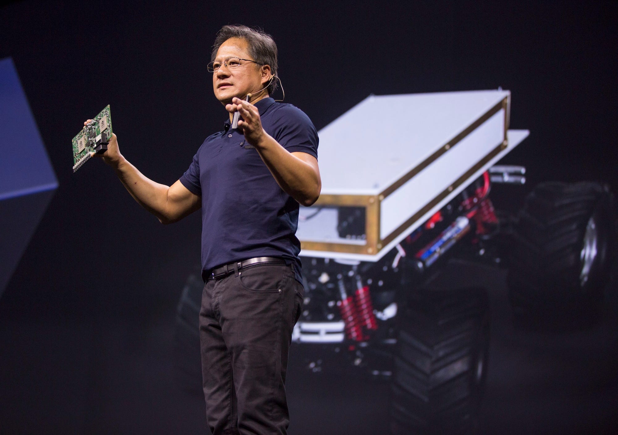 Nvidia's Jensen Huang holds an Nvidia Drive PX Auto-Pilot Computer while giving a speech.