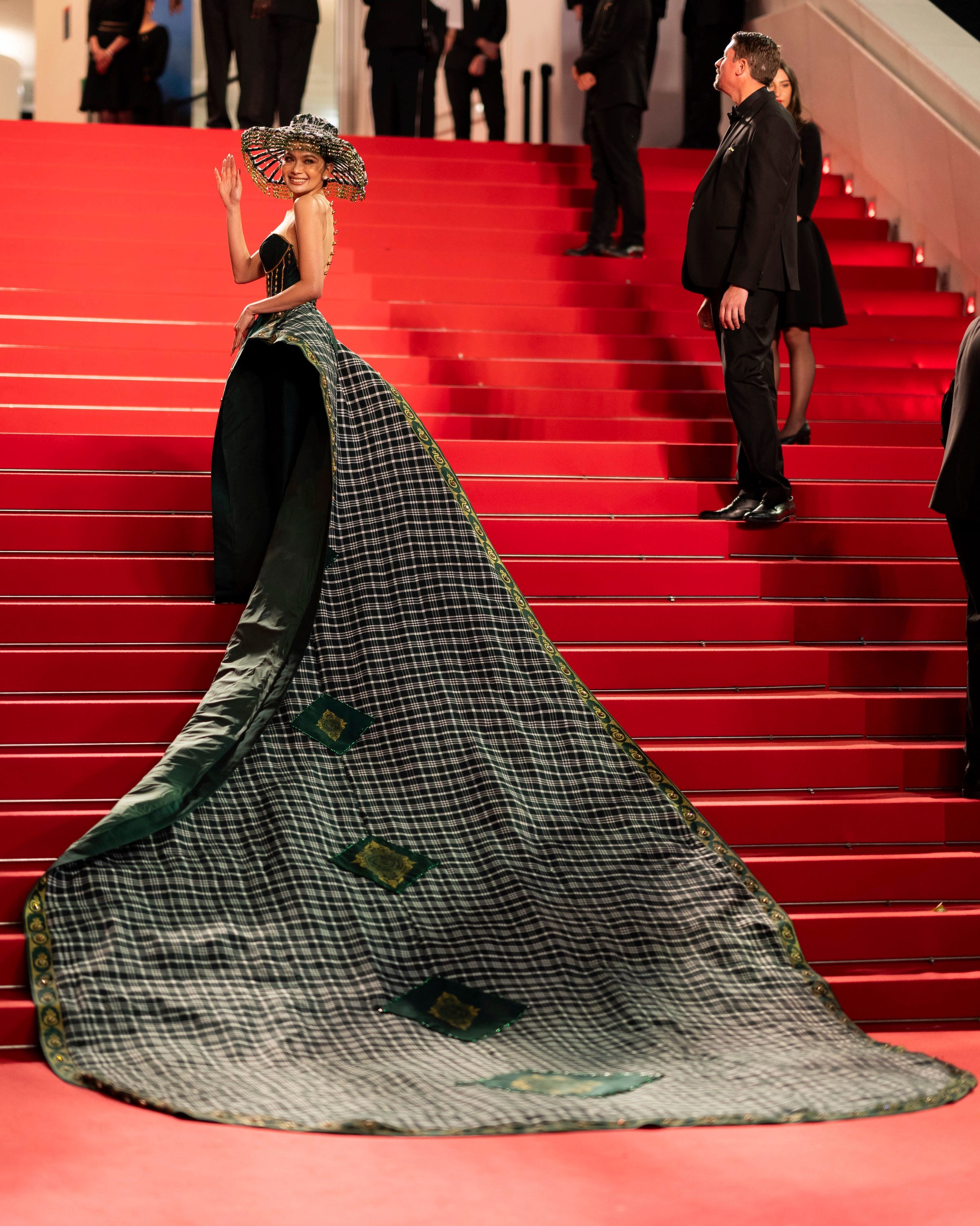 Mean Sonyta waves while the train of her dress cascades down stairs.