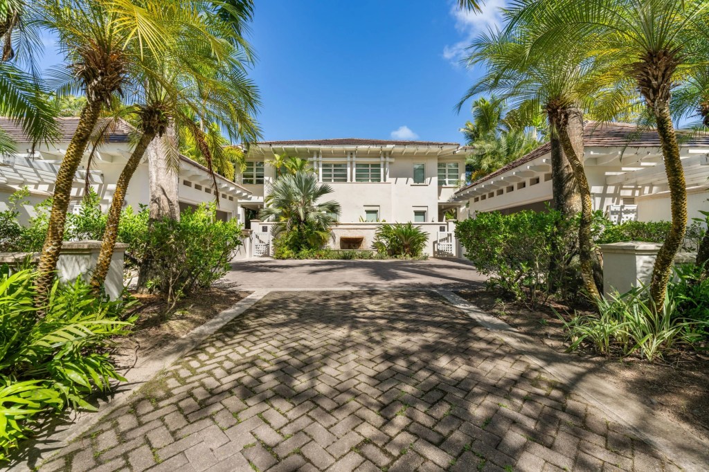 the exterior of the puerto rican townhouse with palms trees lining the walk way and blue sky  above